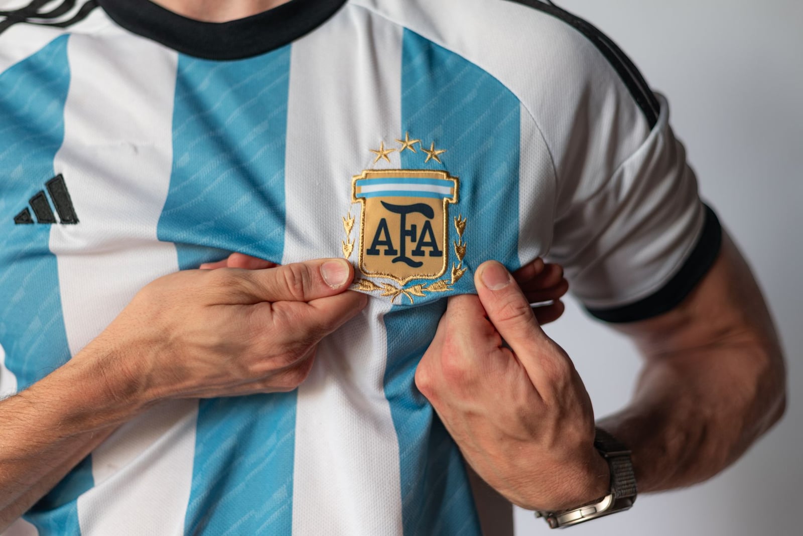Vista detallada de una persona sosteniendo el emblema de una camiseta de fútbol de Argentina, mostrando orgullo nacional.