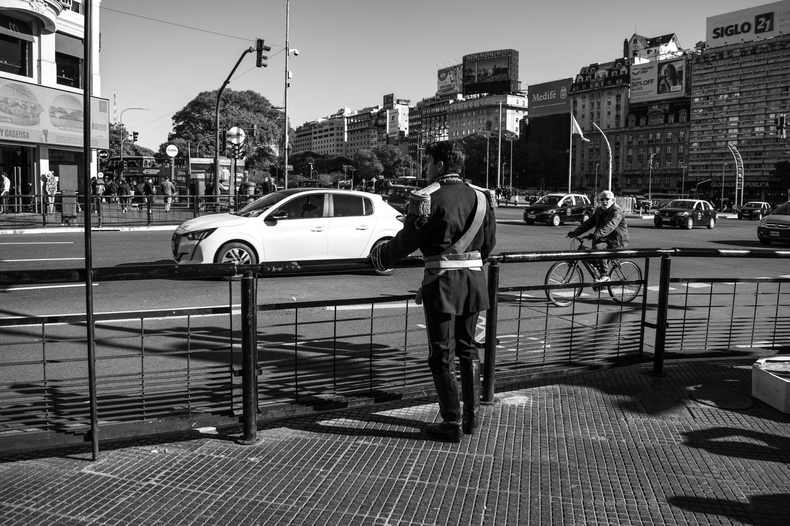 Escena urbana en blanco y negro que muestra a un agente de tráfico y un paisaje urbano bullicioso.