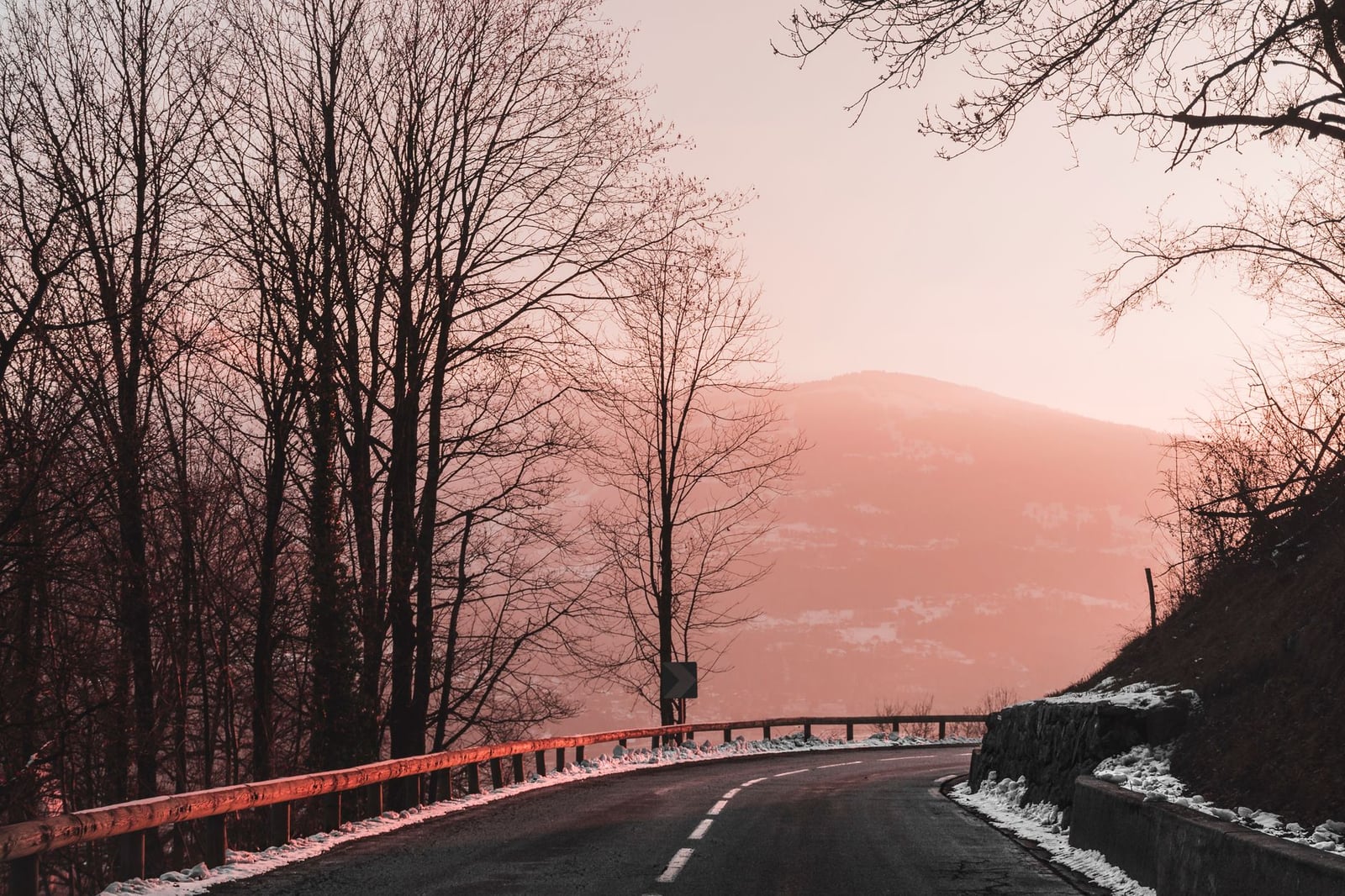 Hermosa vista del atardecer de una carretera nevada que serpentea entre los árboles y las montañas en Chamonix, Francia.