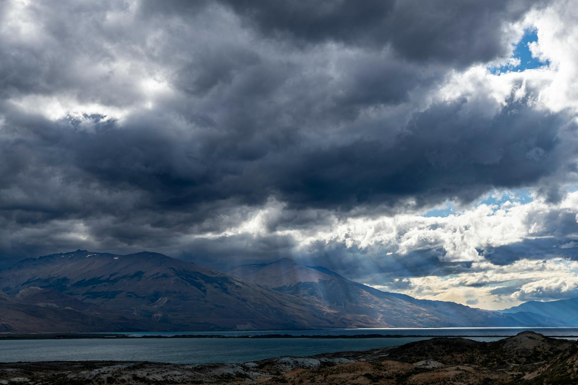 Nubes oscuras proyectan sombras sobre el Lago Posadas en Santa Cruz, Argentina, creando una escena atmosférica de gran dramatismo.
