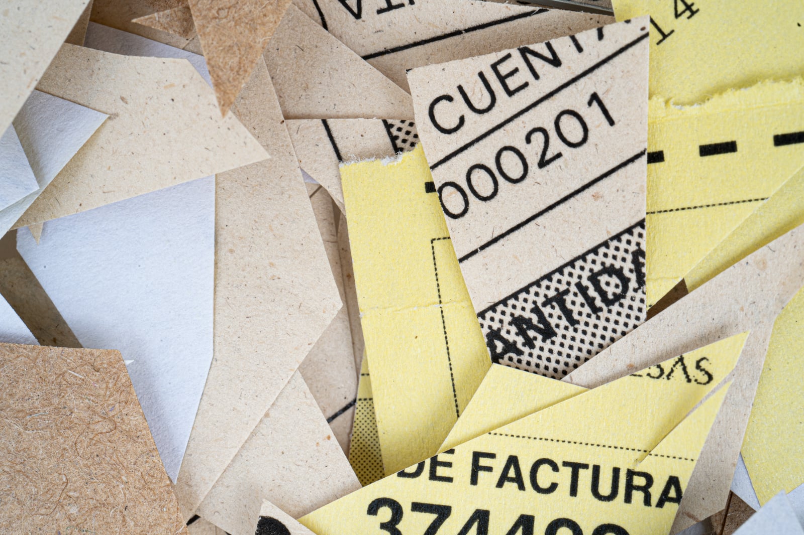 Una pila de trozos de papel rotos mezclados con texto y números visibles en primer plano.