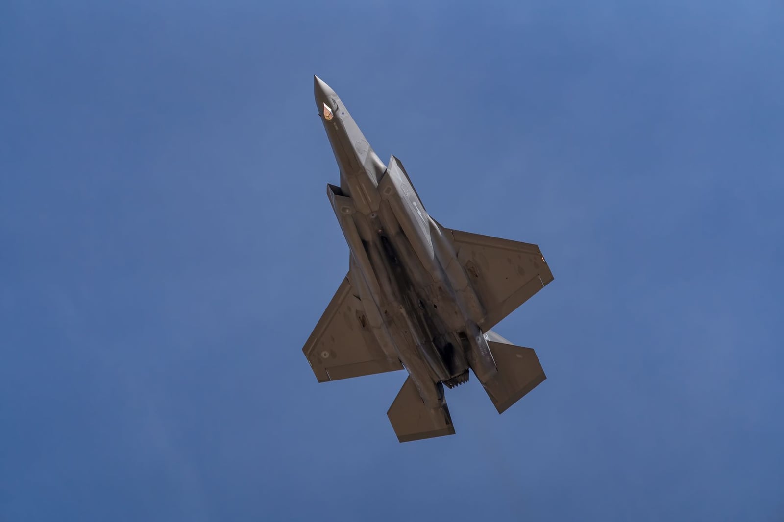 Una captura dinámica de un avión F-35 volando contra un cielo azul claro en Los Llanos, España.