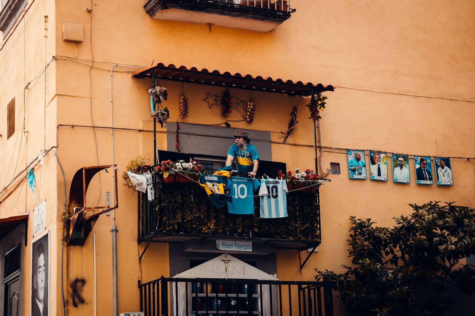 Un balcón decorado con camisetas de fútbol y fotografías de jugadores, que muestra un homenaje a las leyendas del fútbol.