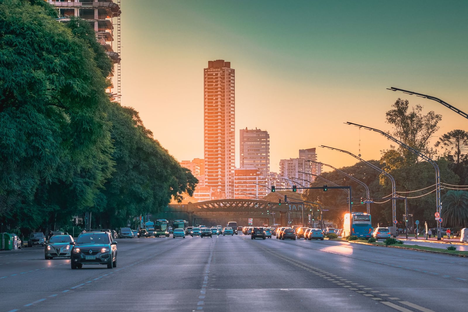 Calle bulliciosa de la ciudad con tráfico y rascacielos al atardecer, capturando la vida urbana y la arquitectura.