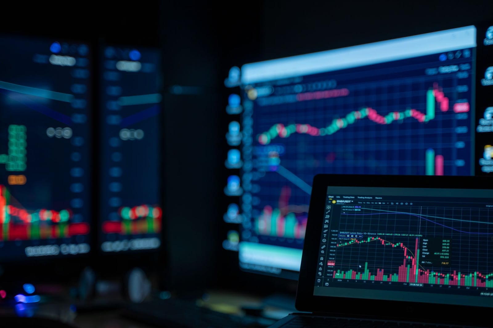 Monitores que muestran gráficos del mercado de valores en una habitación con poca luz, perfectos para temas de finanzas y comercio.