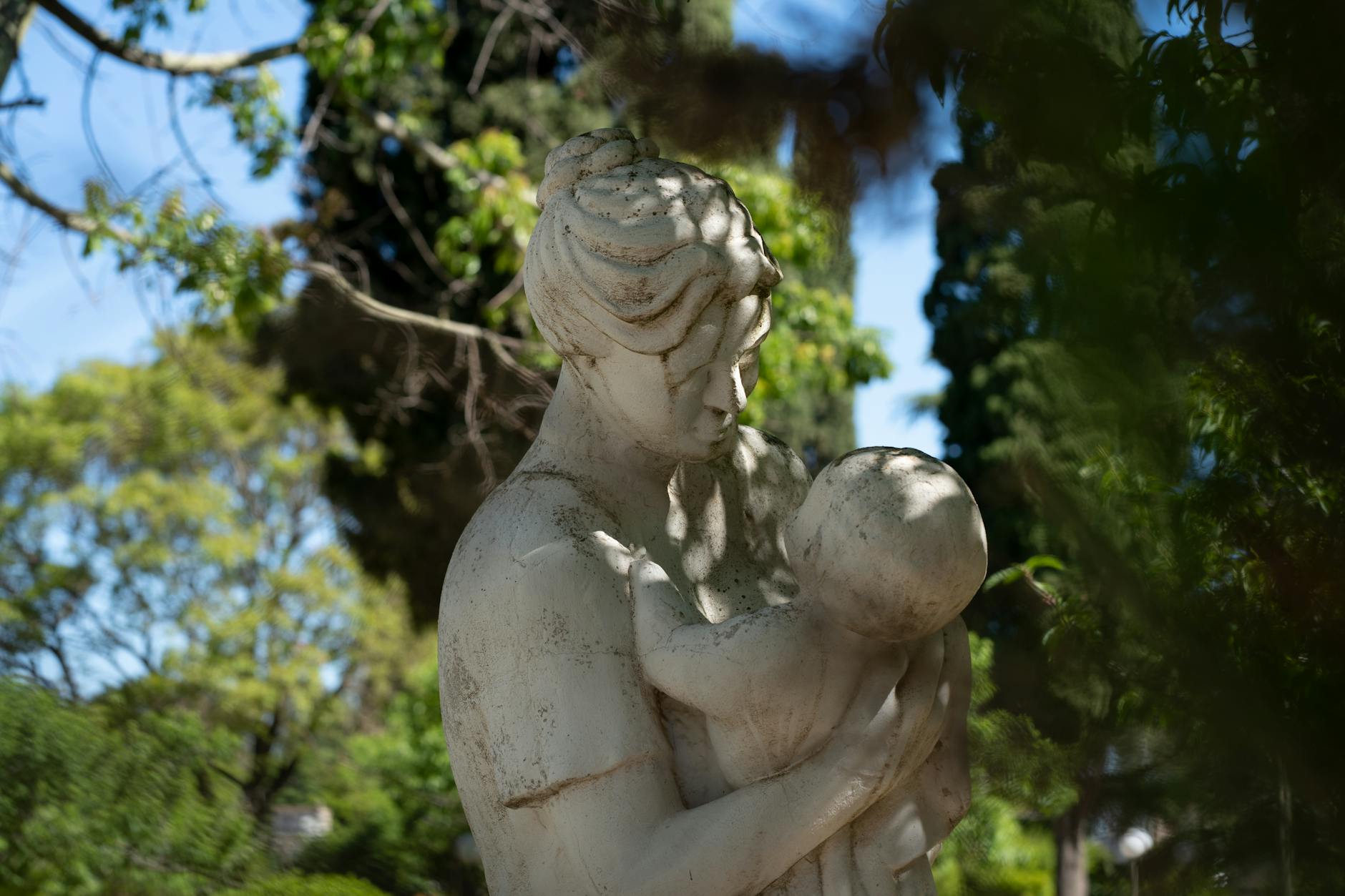 Una serena estatua de una madre y su hijo rodeada de vegetación en Morrison, Argentina.