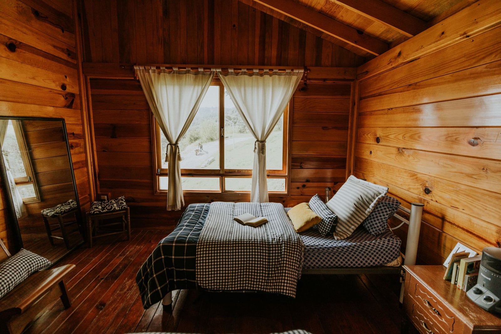 Dormitorio en cabaña de madera cálido y acogedor que ofrece una vista panorámica al aire libre con luz natural.