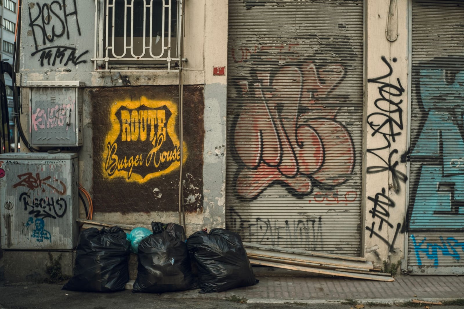 Esquina de calle cubierta de graffiti con bolsas de basura contra una pared. Decadencia urbana a plena luz del día.