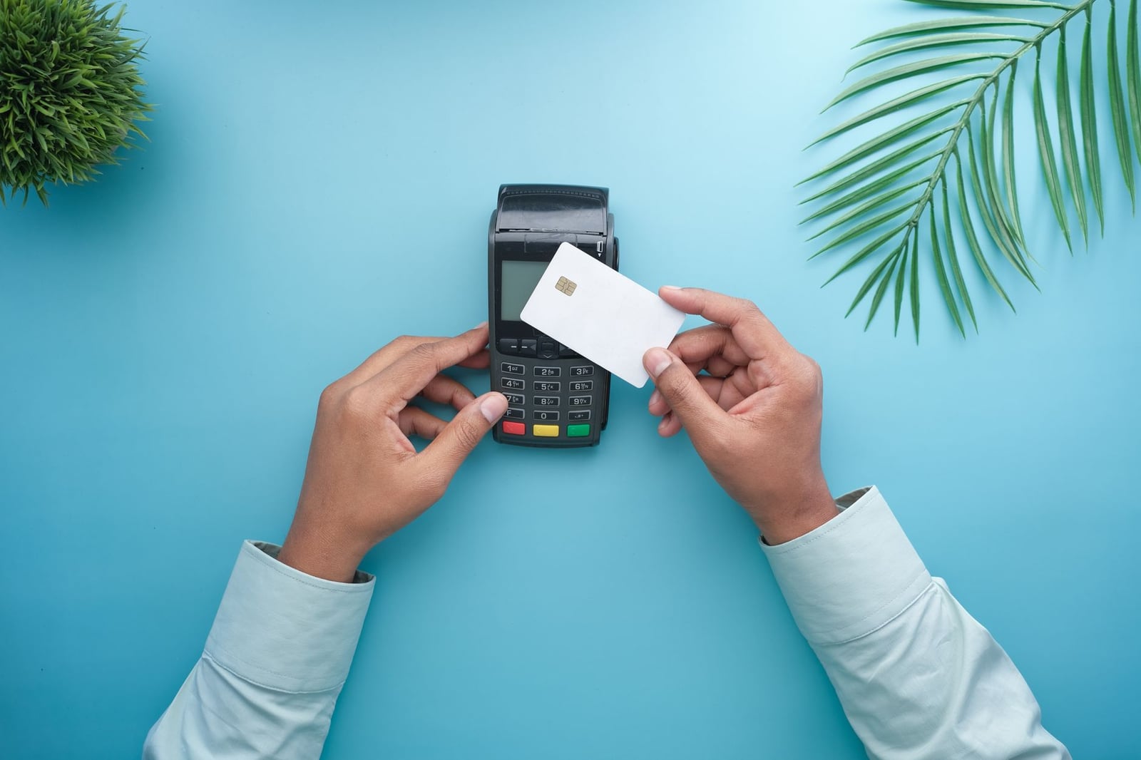 Manos usando una tarjeta de crédito sin contacto en un terminal de pago con un fondo minimalista y elegante.