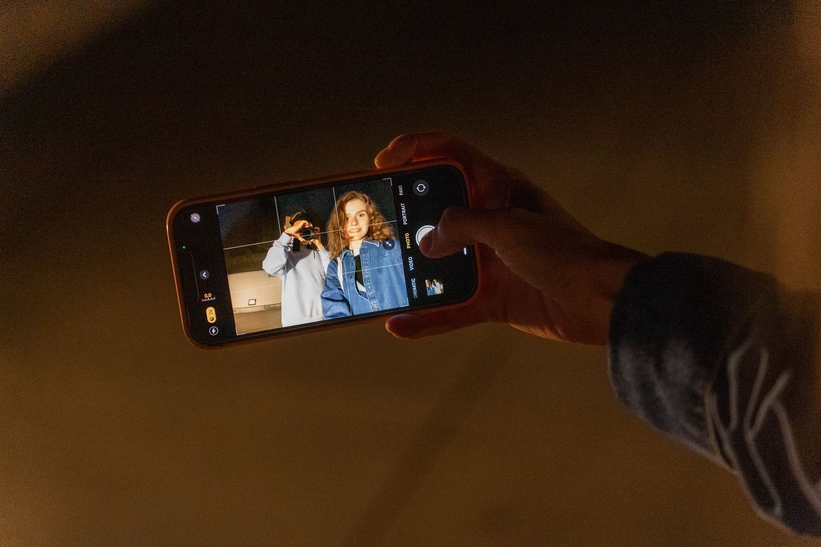 Una pareja capturando un recuerdo romántico con la cámara de un smartphone durante la noche en interiores.