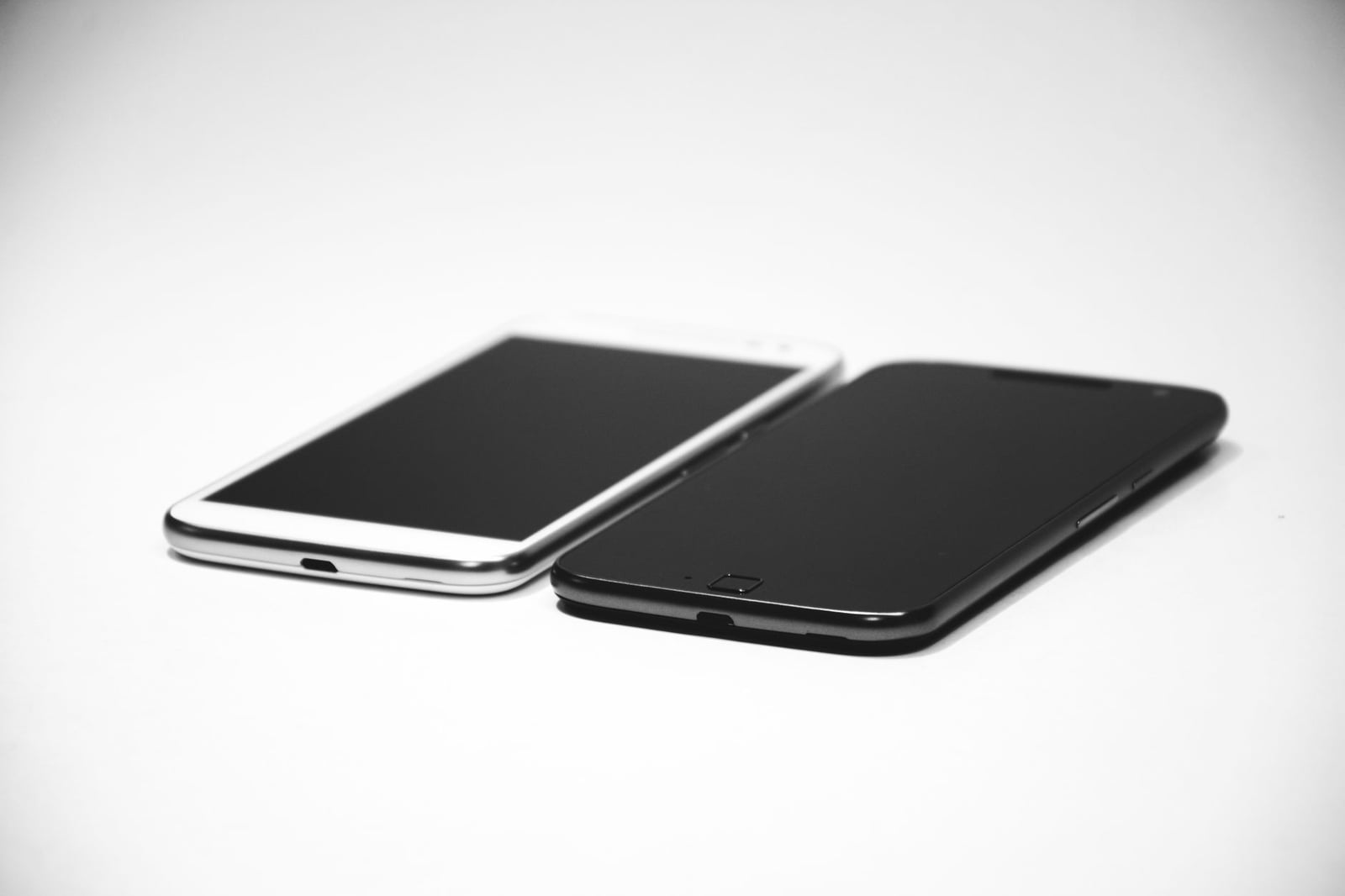Dos smartphones, uno negro y uno blanco, colocados sobre una superficie blanca, mostrando un diseño moderno.
