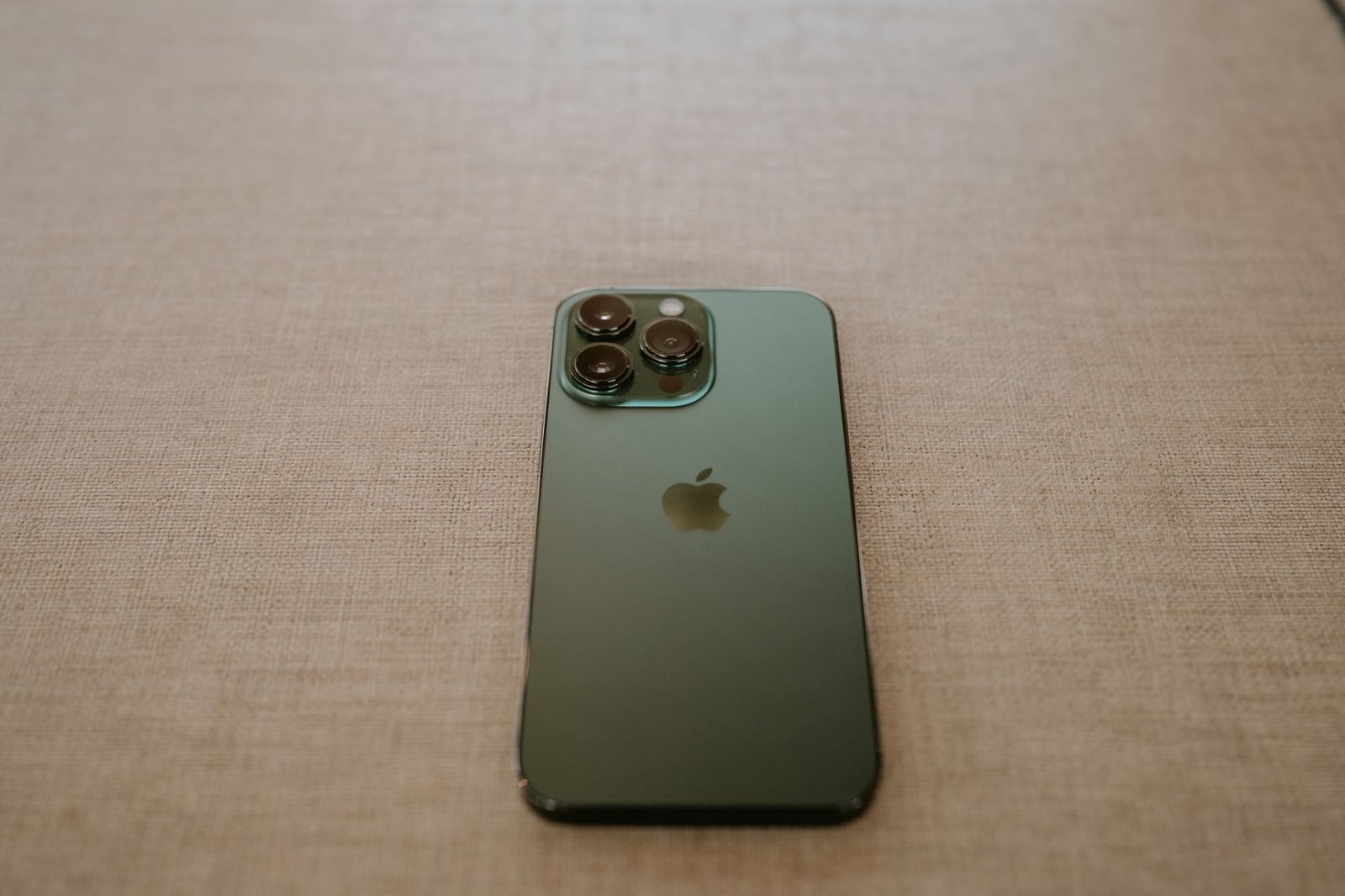 Foto de primer plano de un smartphone verde colocado sobre una superficie texturizada beige.