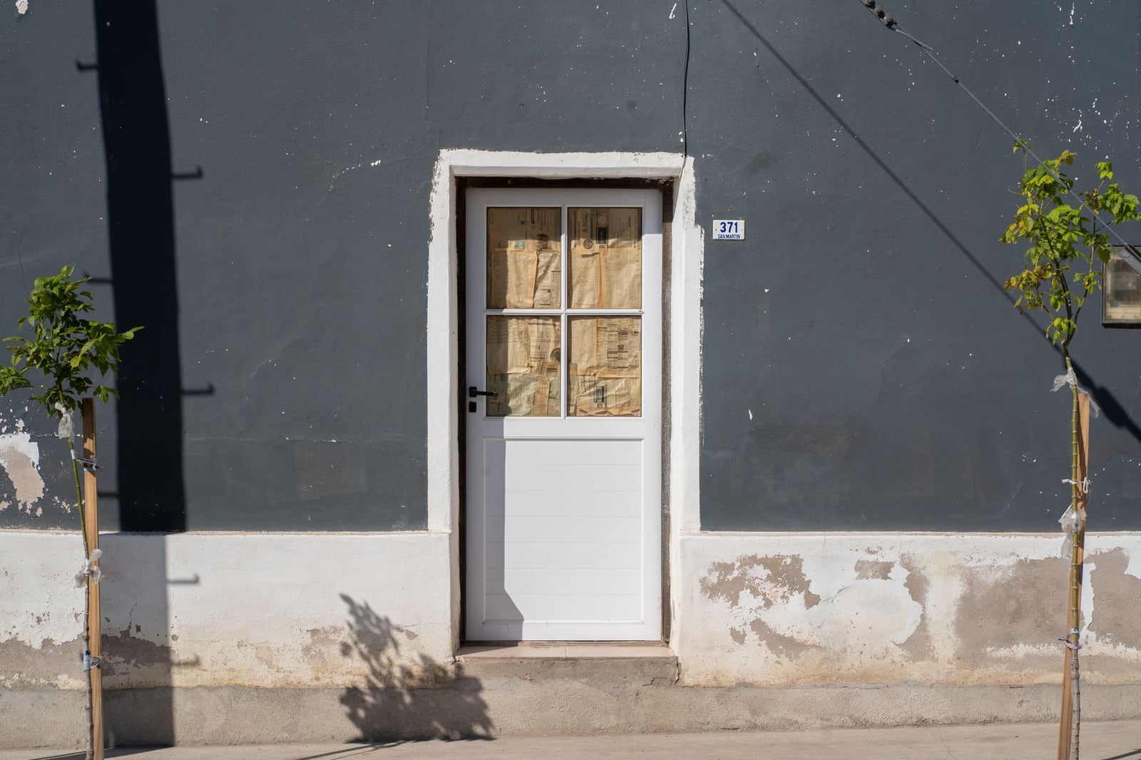 Fotografía de una puerta rústica blanca sobre una fachada gris en La Cruz, Córdoba, Argentina.