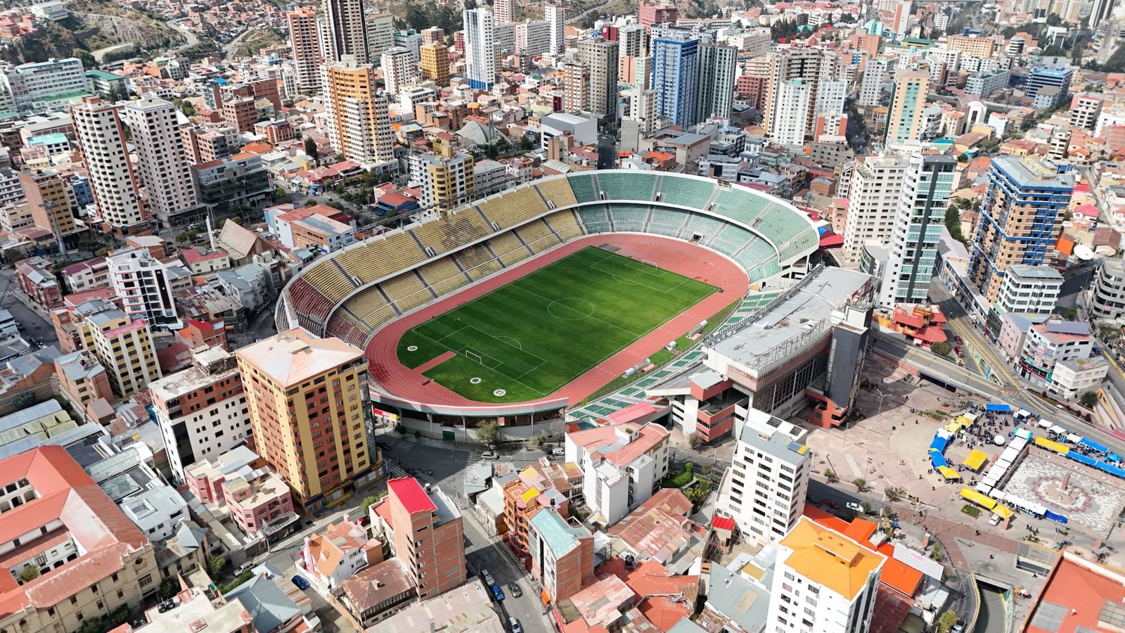 Toma aérea de un estadio en La Paz, Bolivia, rodeado de rascacielos y paisaje urbano.