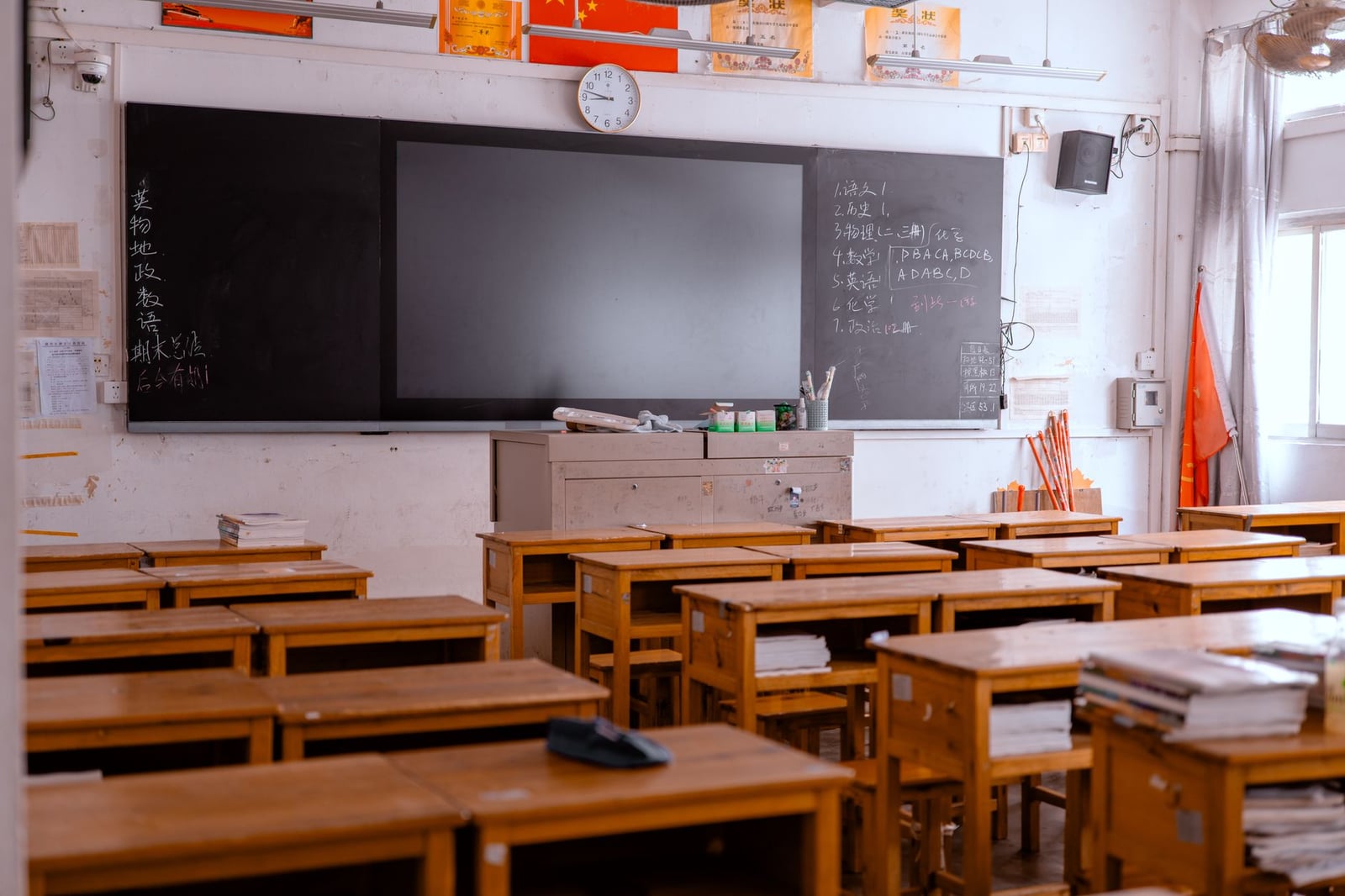Una aula vacía con escritorios de madera y una pizarra, que presenta materiales educativos.