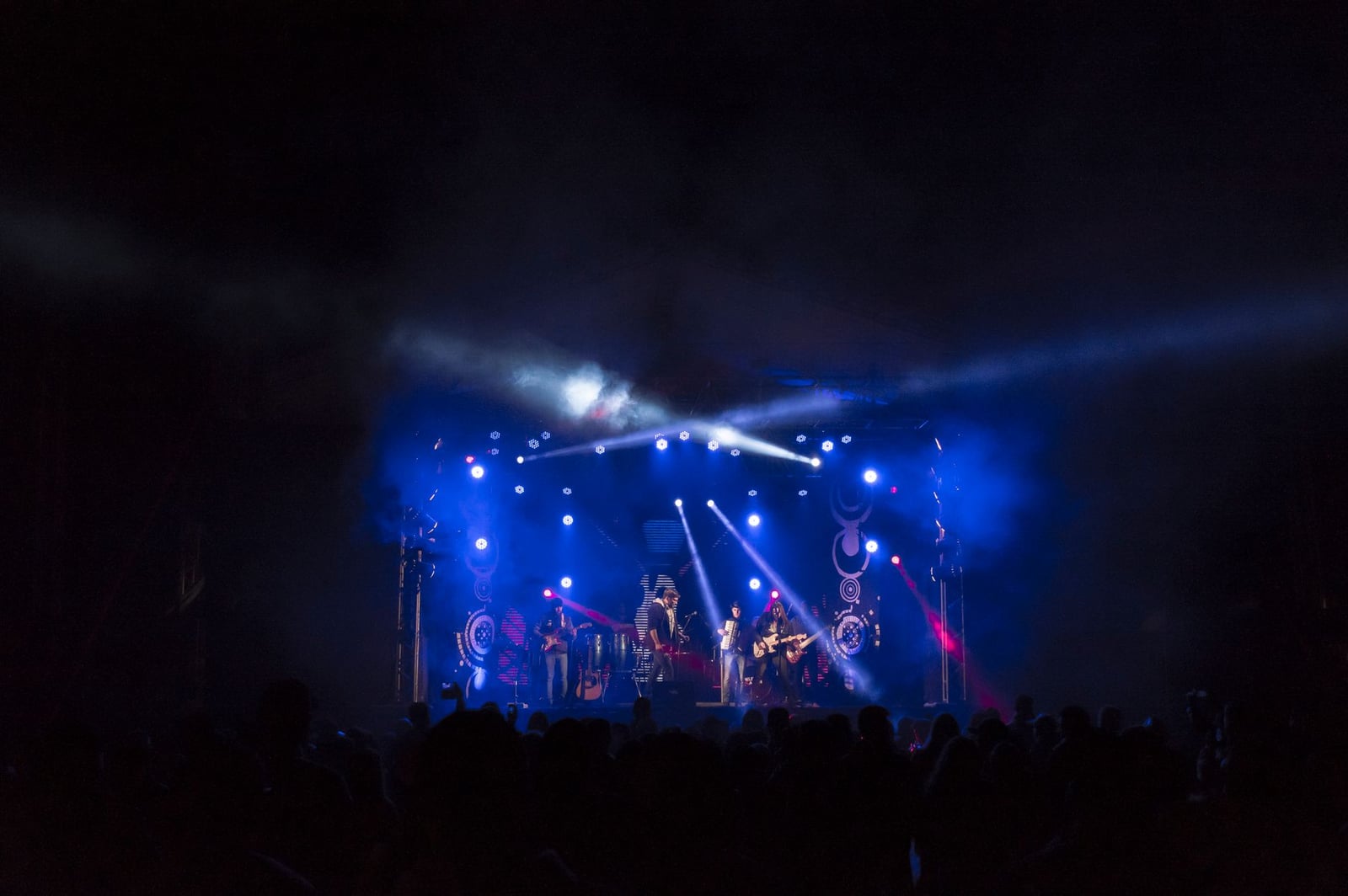 Actuación de banda enérgica en un escenario con luces coloridas y una multitud comprometida.