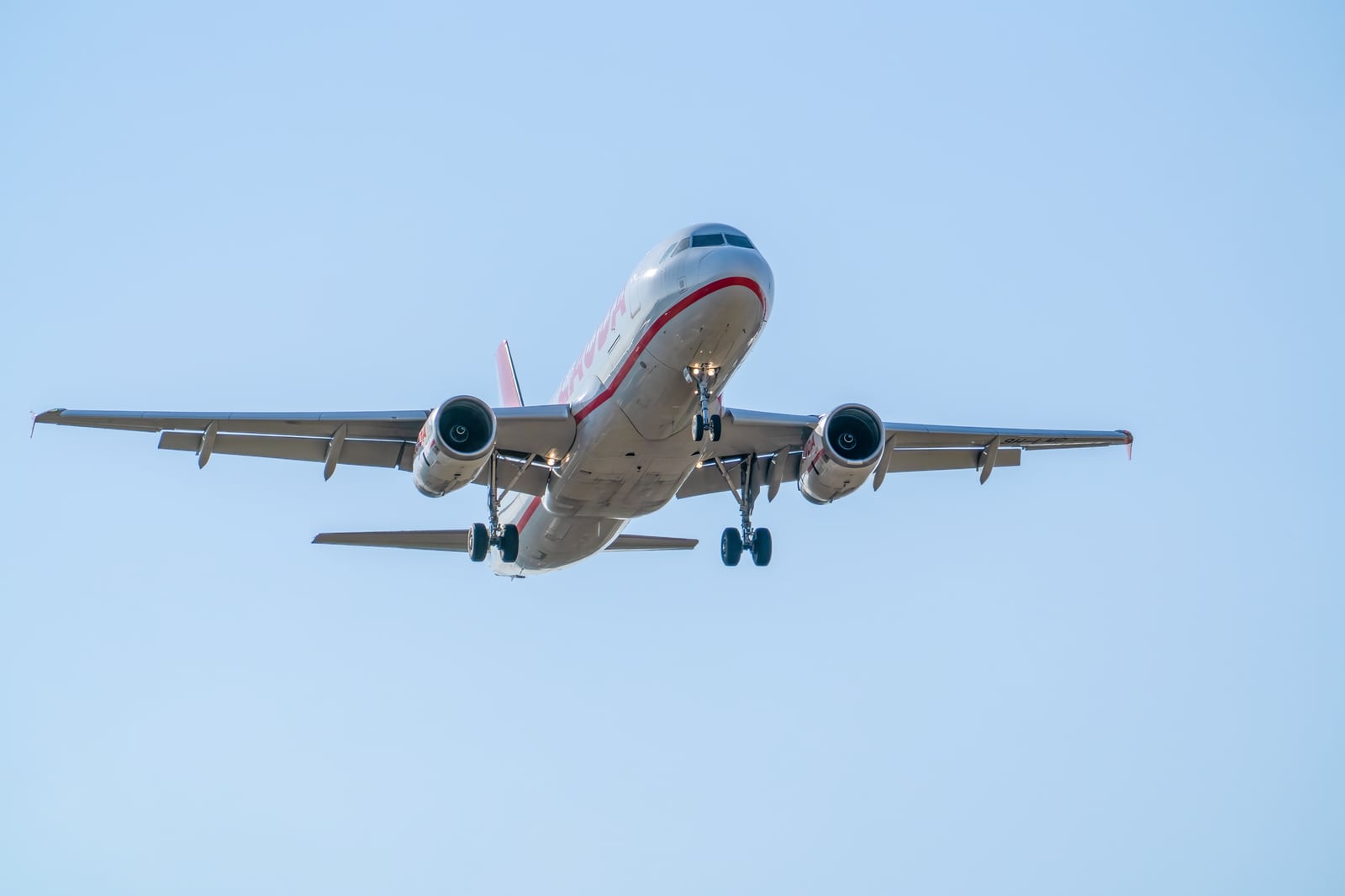 Un Airbus A320 en vuelo descendiendo sobre Manises, Valencia. Cielo azul despejado.