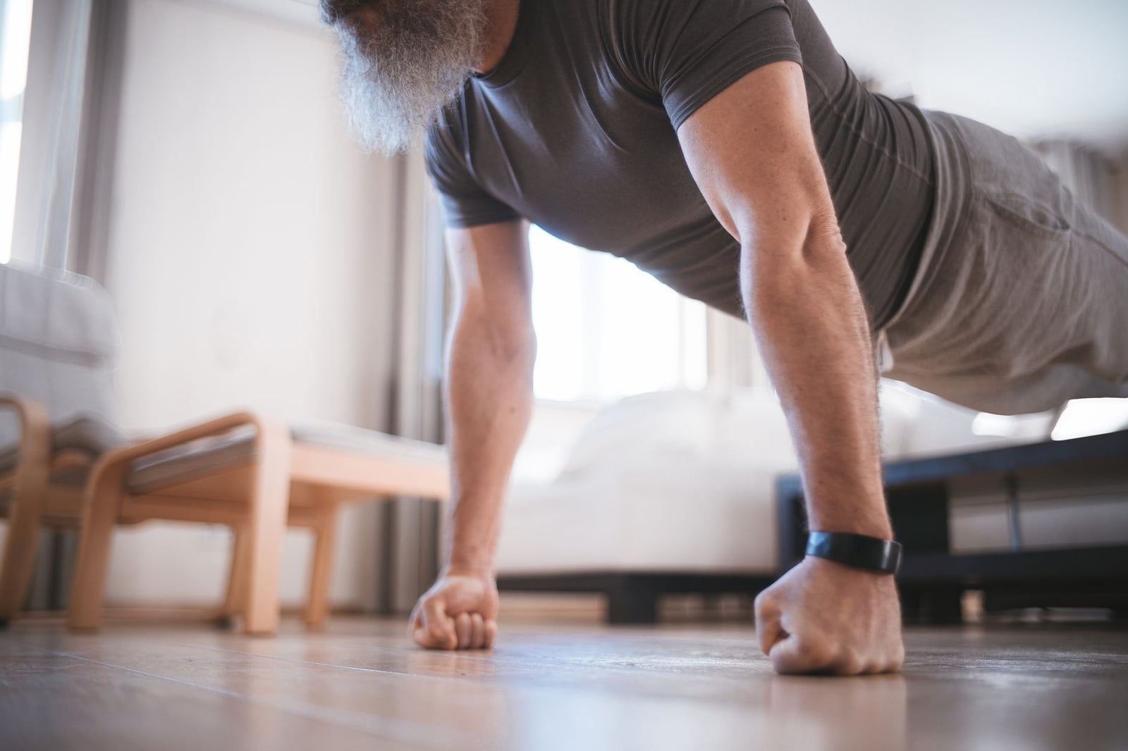 Un hombre mayor realizando flexiones en el suelo de su sala de estar para estar en forma.