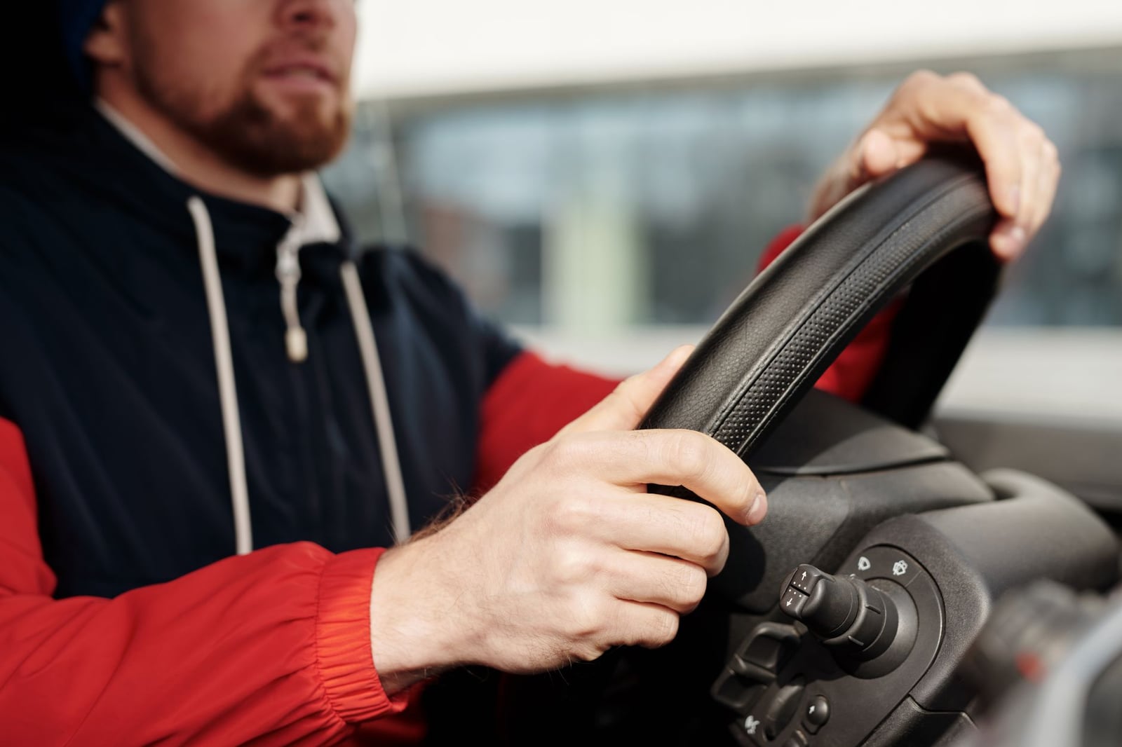 Hombre enfocado sosteniendo el volante, conduciendo en el interior del vehículo. Vista cercana con profundidad selectiva.