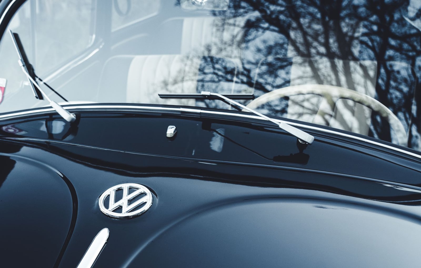 Primer plano de un clásico Volkswagen Escarabajo azul oscuro con el emblema VW. Captura la esencia del diseño automotriz vintage.