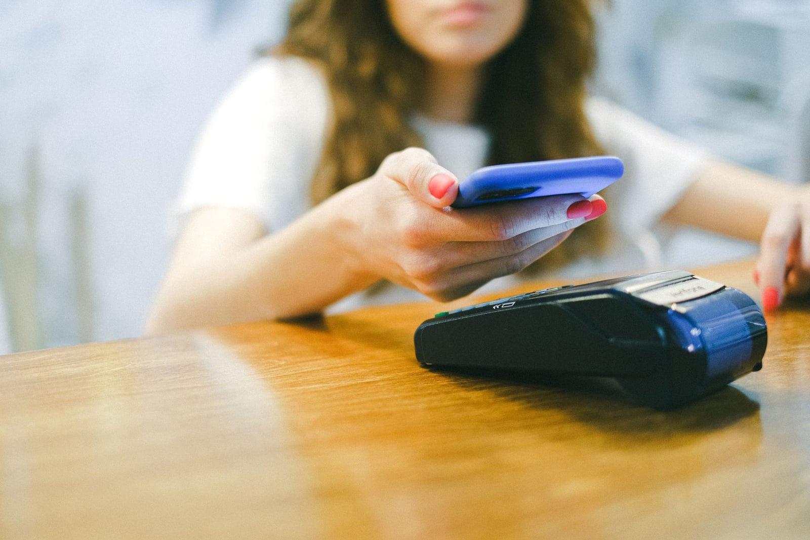 Una mujer realiza un pago sin contacto utilizando su smartphone en un terminal de pago.