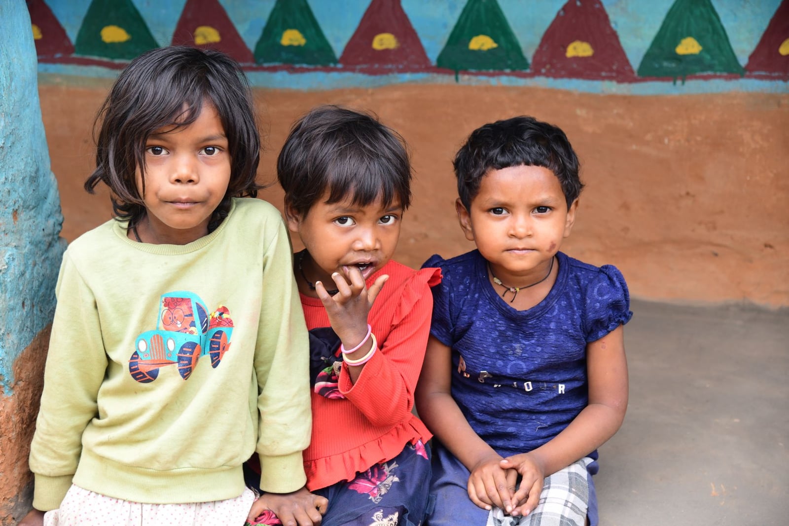 Tres niños alegres posan en un entorno vibrante, reflejando calidez e inocencia cultural.