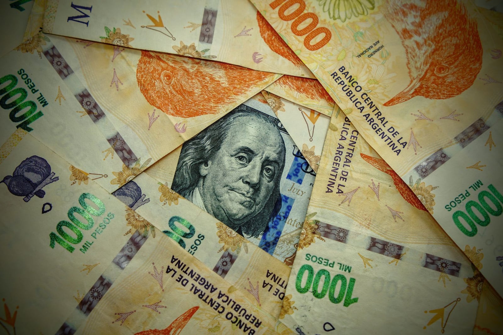 Un primer plano detallado de pesos argentinos y un dólar estadounidense, mostrando el contraste de las monedas.