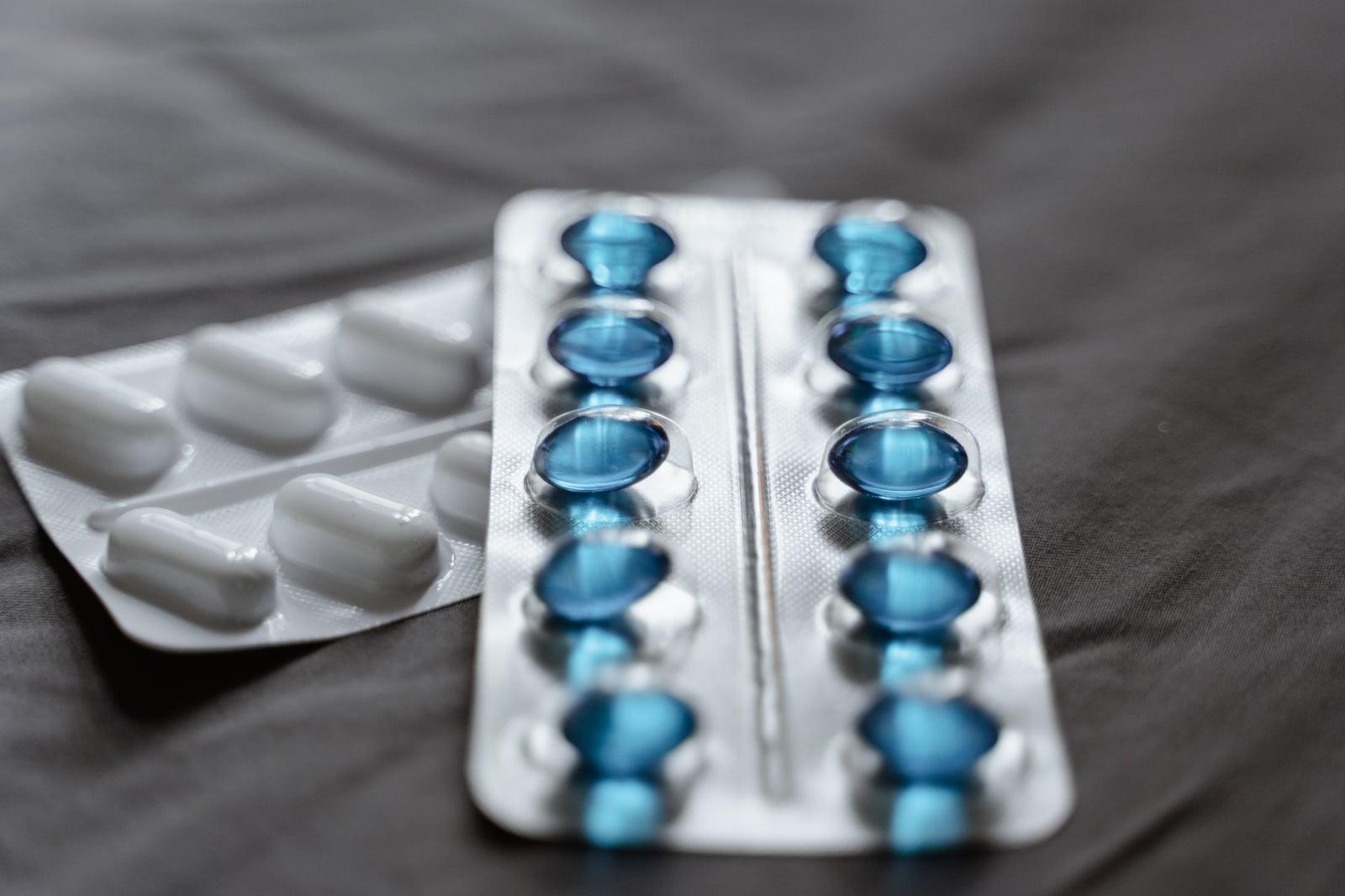 Vista detallada de medicamentos en blíster que muestra cápsulas de softgel azules y pastillas blancas.