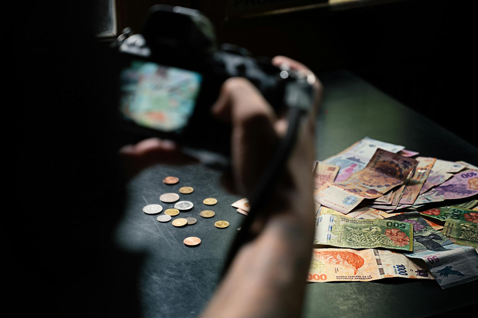 Primer plano de billetes y monedas de pesos argentinos fotografiados en interiores.