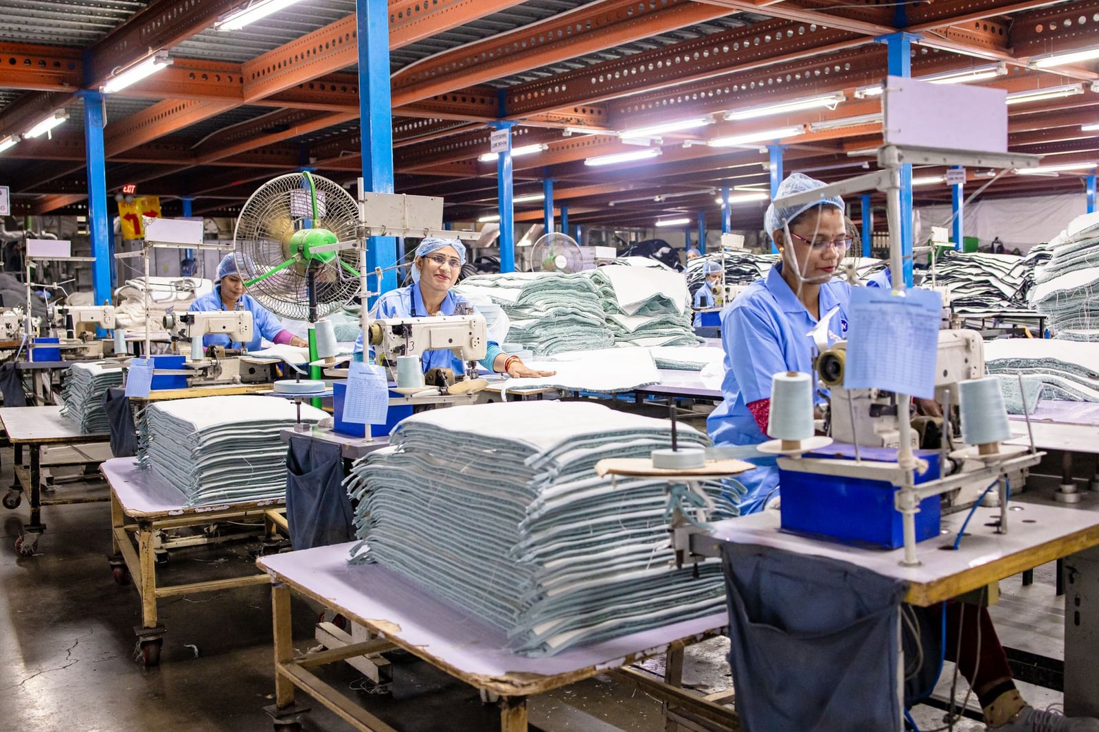 Trabajadores de una fábrica textil operando máquinas de coser y organizando telas.