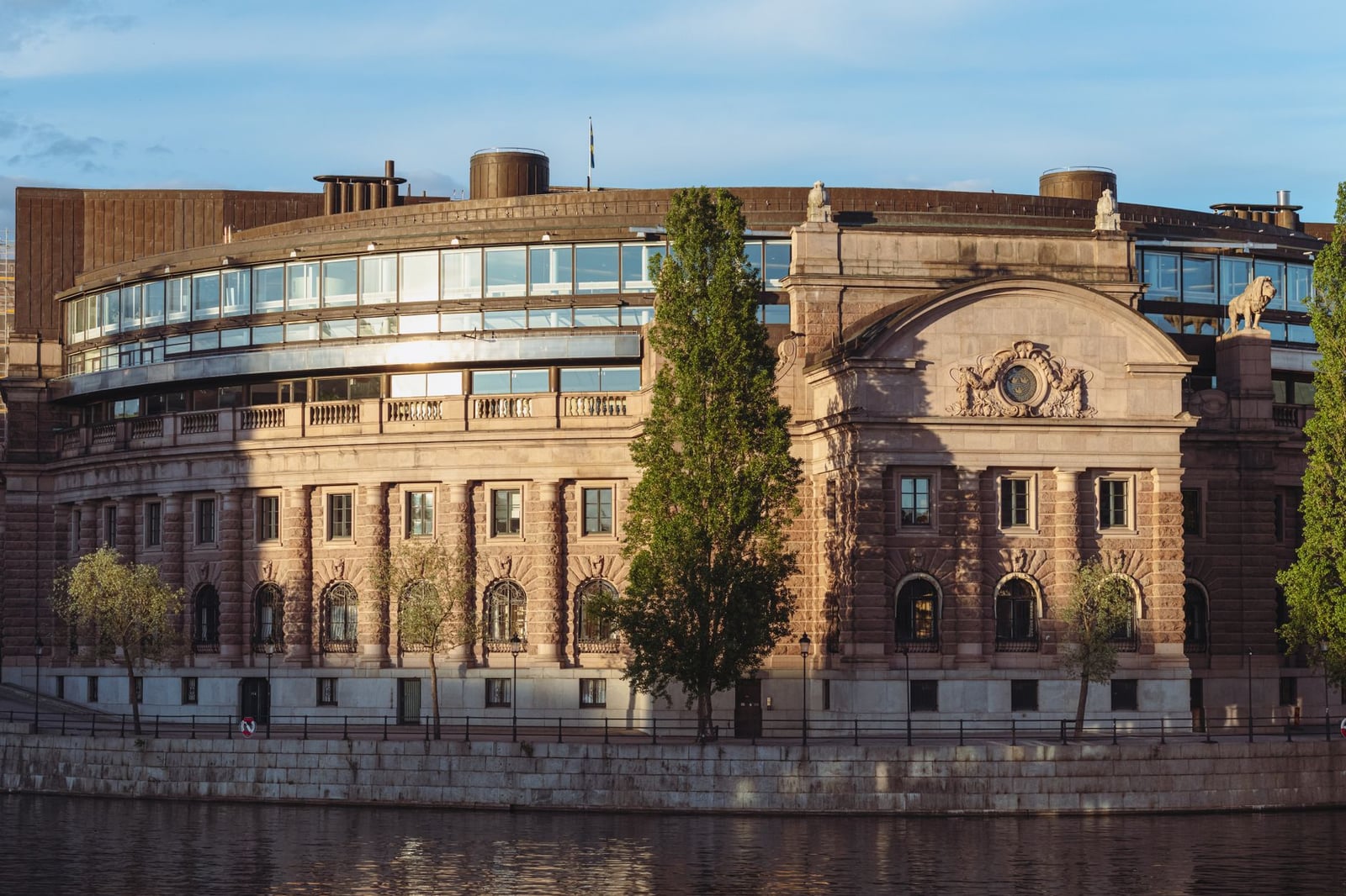 El Parlamento sueco junto al paseo marítimo, con la cálida luz del atardecer en Estocolmo.
