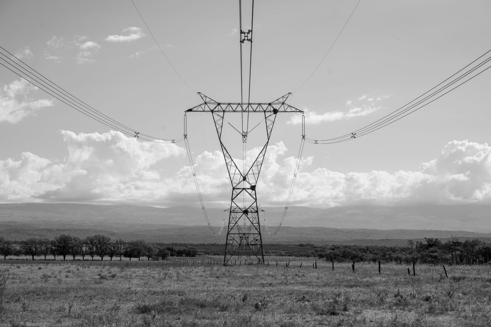 Imagen en blanco y negro de una torre de transmisión eléctrica en un vasto paisaje de Córdoba, Argentina.