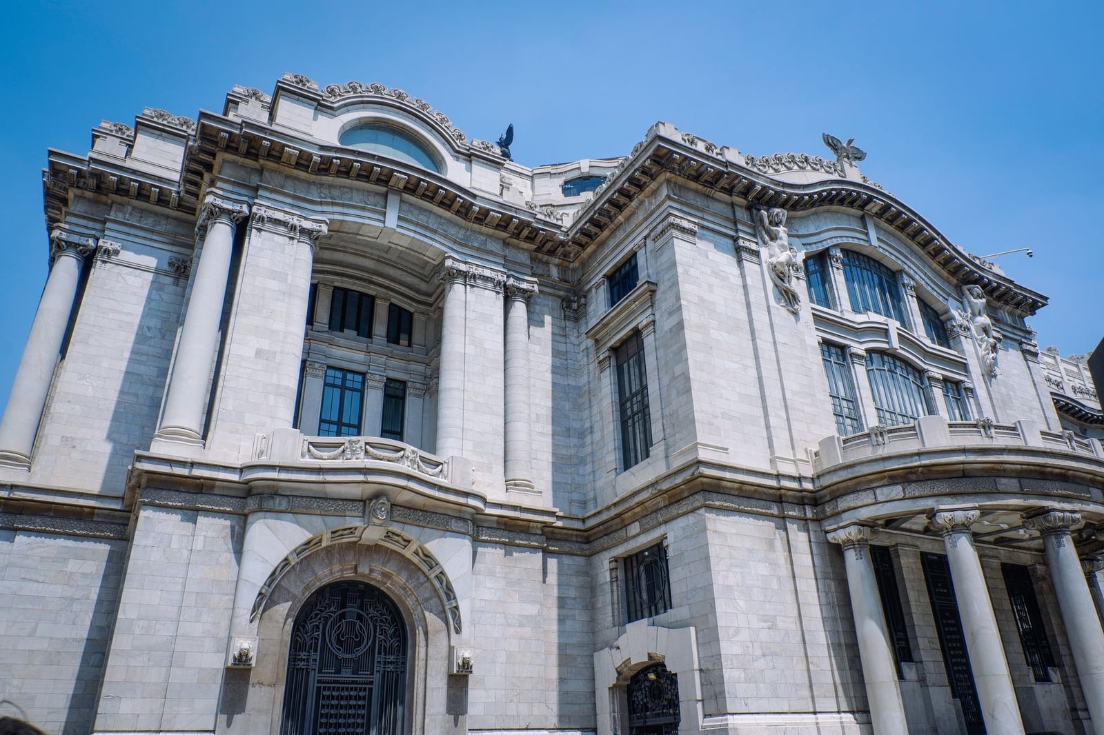 Impresionante vista de la arquitectura neoclásica del Palacio de Bellas Artes bajo un cielo azul claro en Ciudad de México.