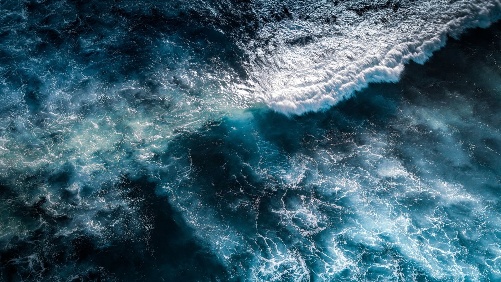 Toma aérea dramática que muestra el movimiento dinámico de las olas del océano chocando entre sí.