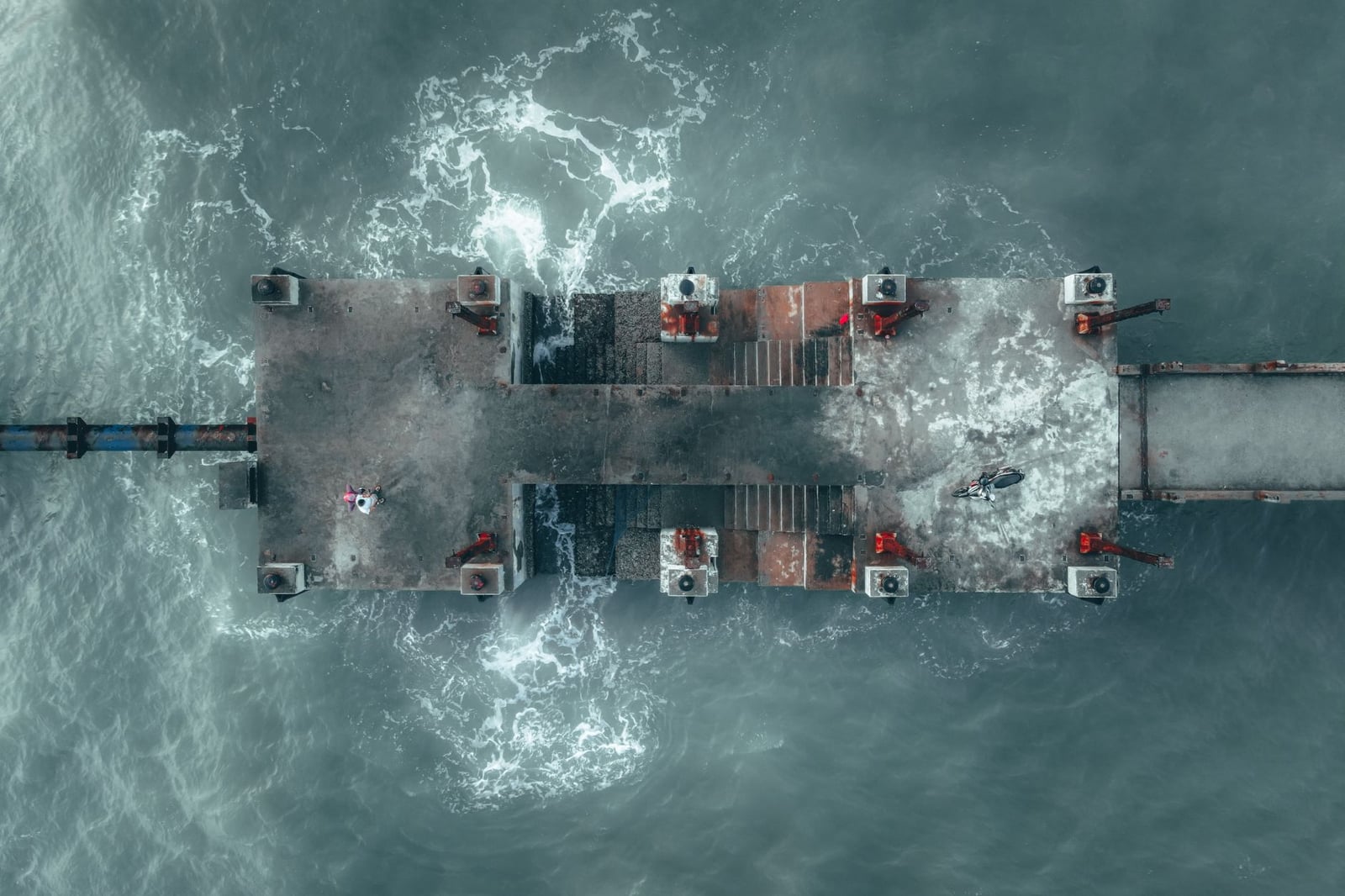 Toma aérea de una plataforma sobre el mar en Malasia, mostrando el movimiento del agua y la estructura industrial.