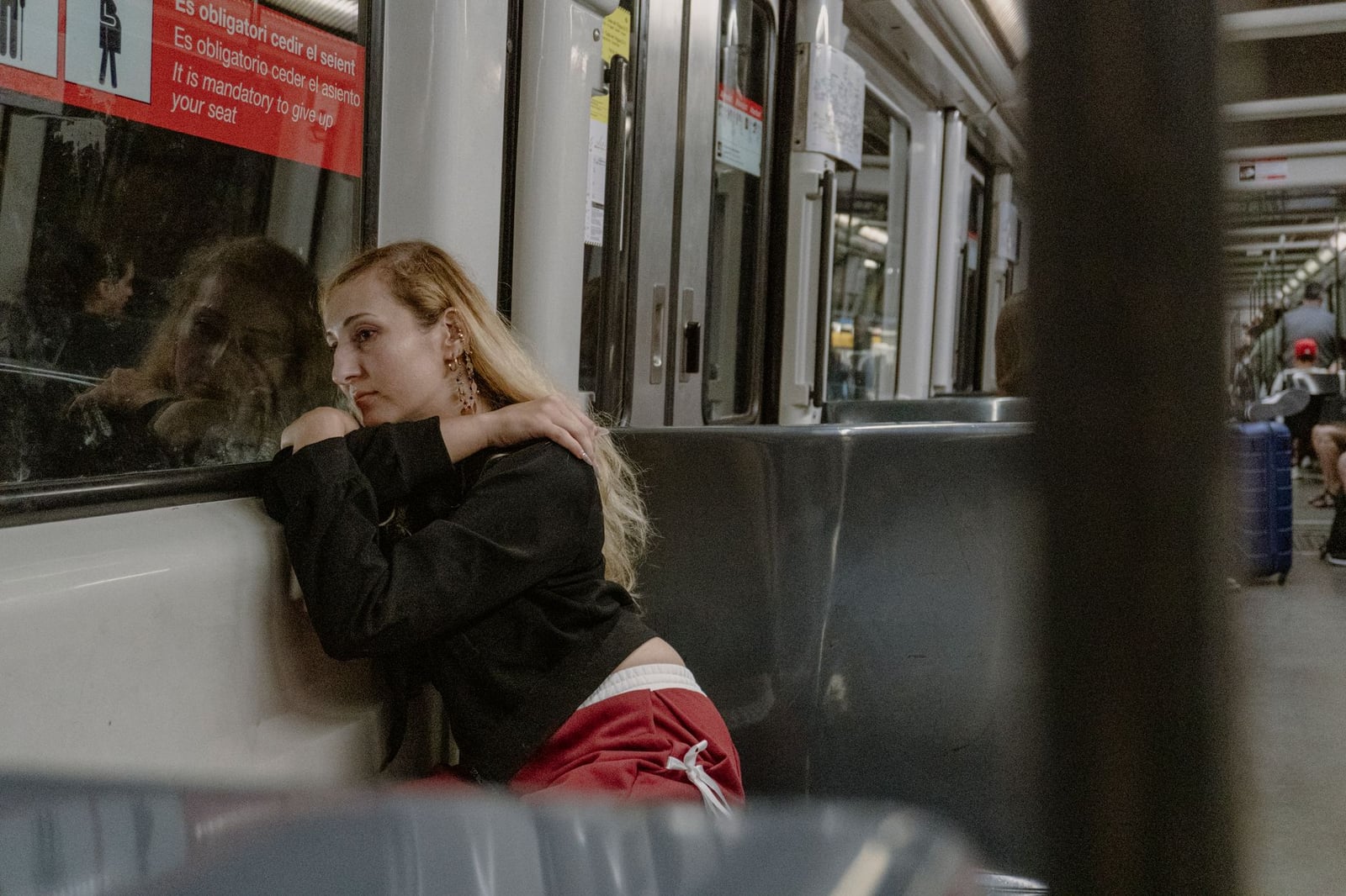 Una mujer perdida en sus pensamientos, apoyada en una ventana del metro de Barcelona, transmite soledad urbana.