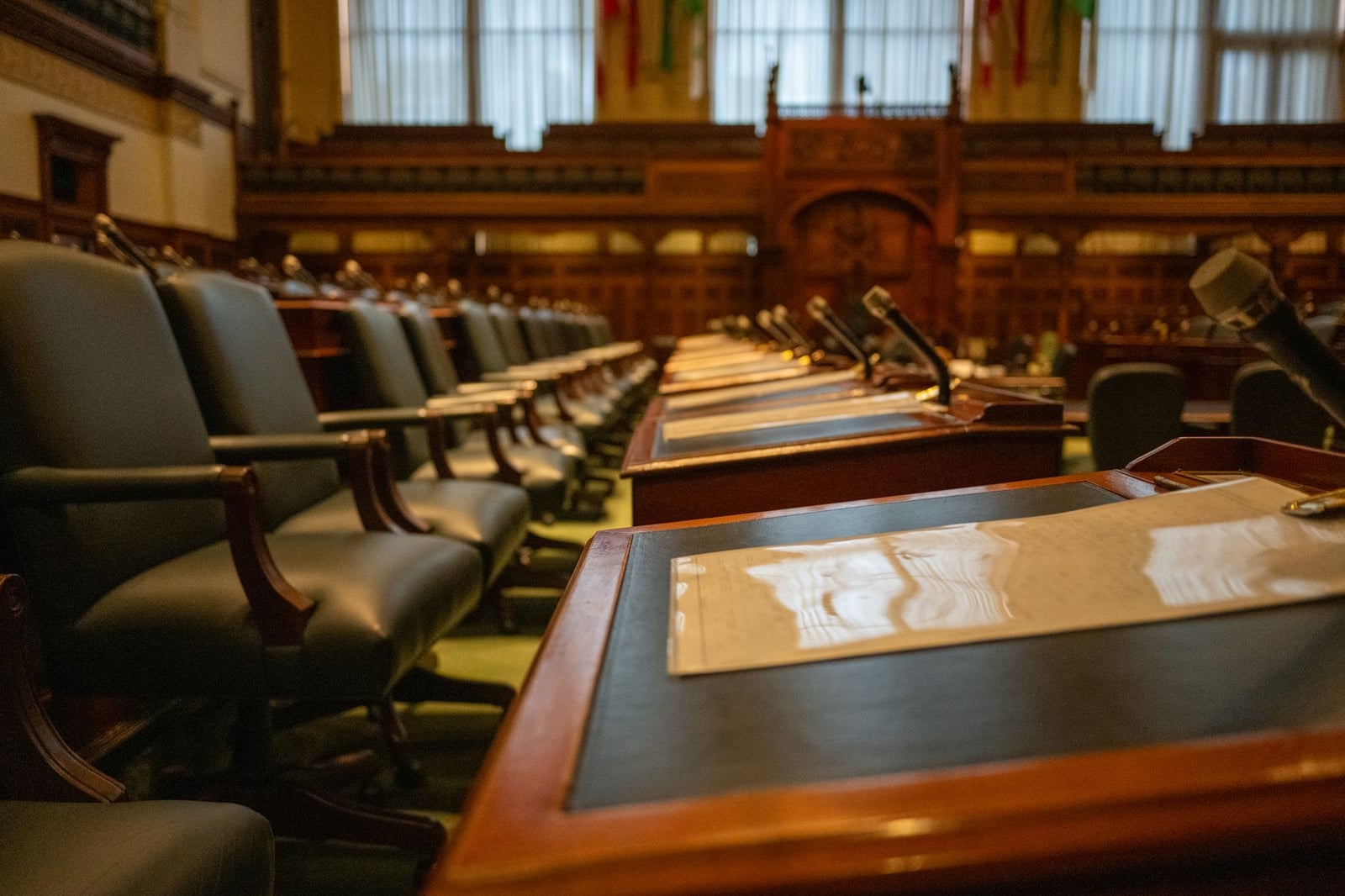 Una vista detallada de una cámara legislativa vacía con filas de escritorios y micrófonos, evocando la gobernanza.