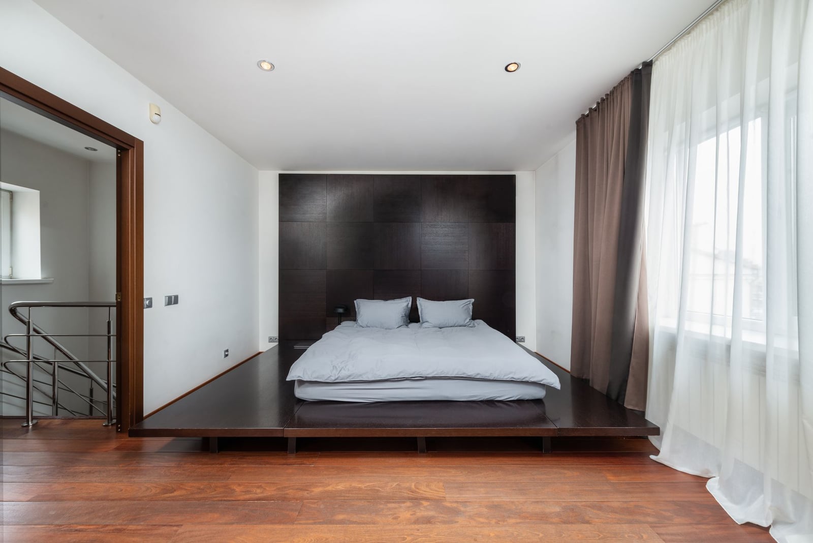 Dormitorio moderno minimalista con suelo de madera y una cama acogedora.