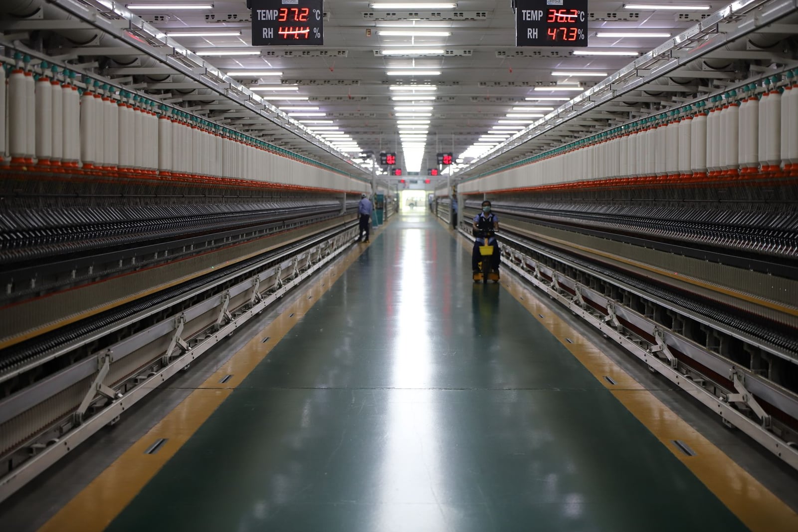 Amplio pasillo de maquinaria textil en una planta industrial india que muestra equipos avanzados.