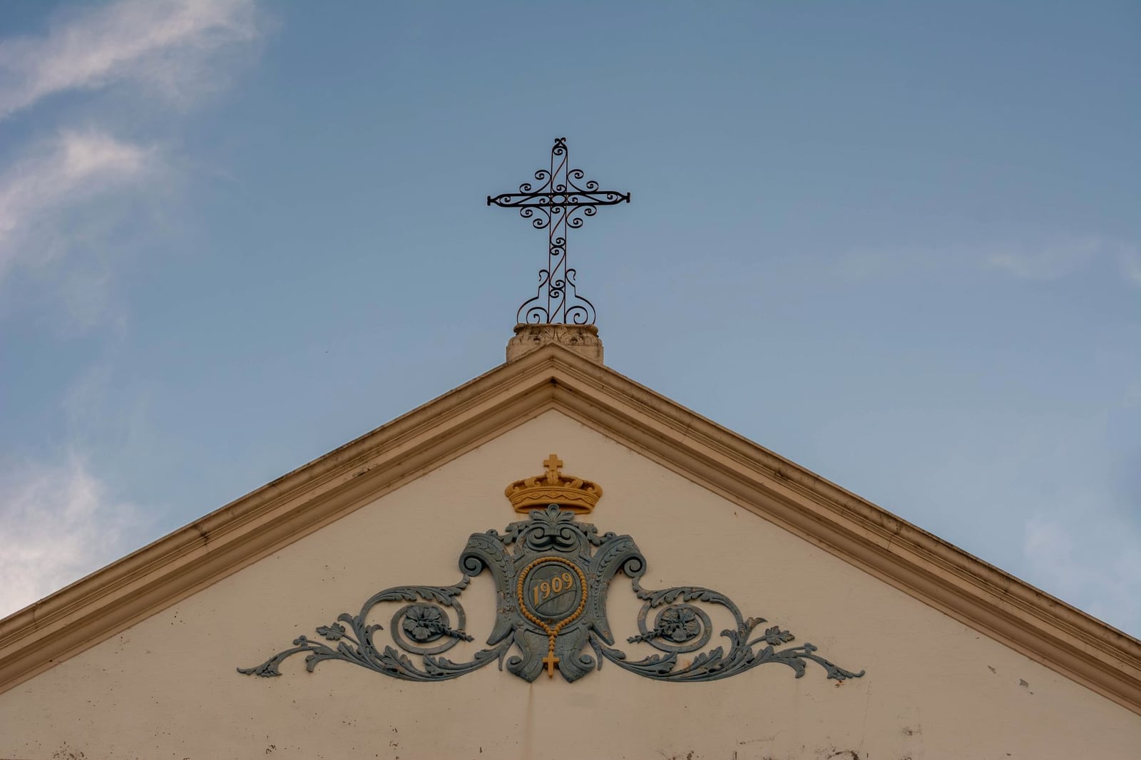 Elegante fachada de iglesia con cruz y escudo decorativos en Santa Luzia, Minas Gerais.