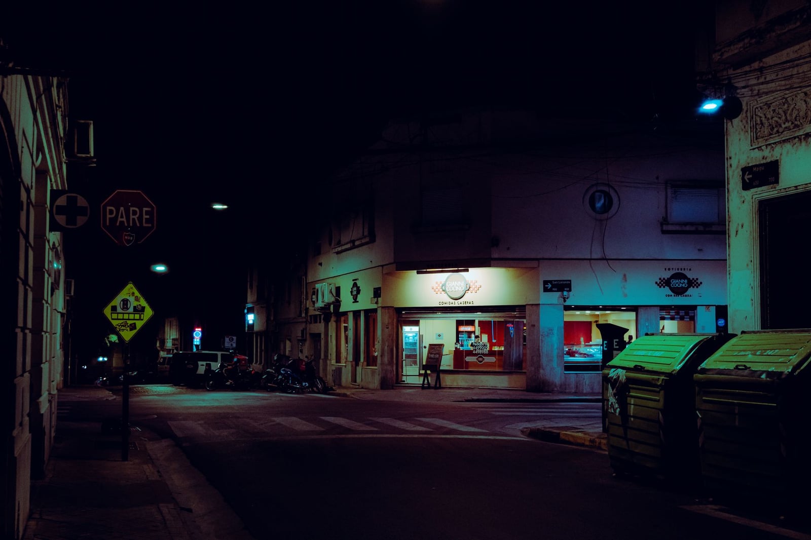 Escena nocturna melancólica de una calle en Rosario, Argentina, con luces de néon.