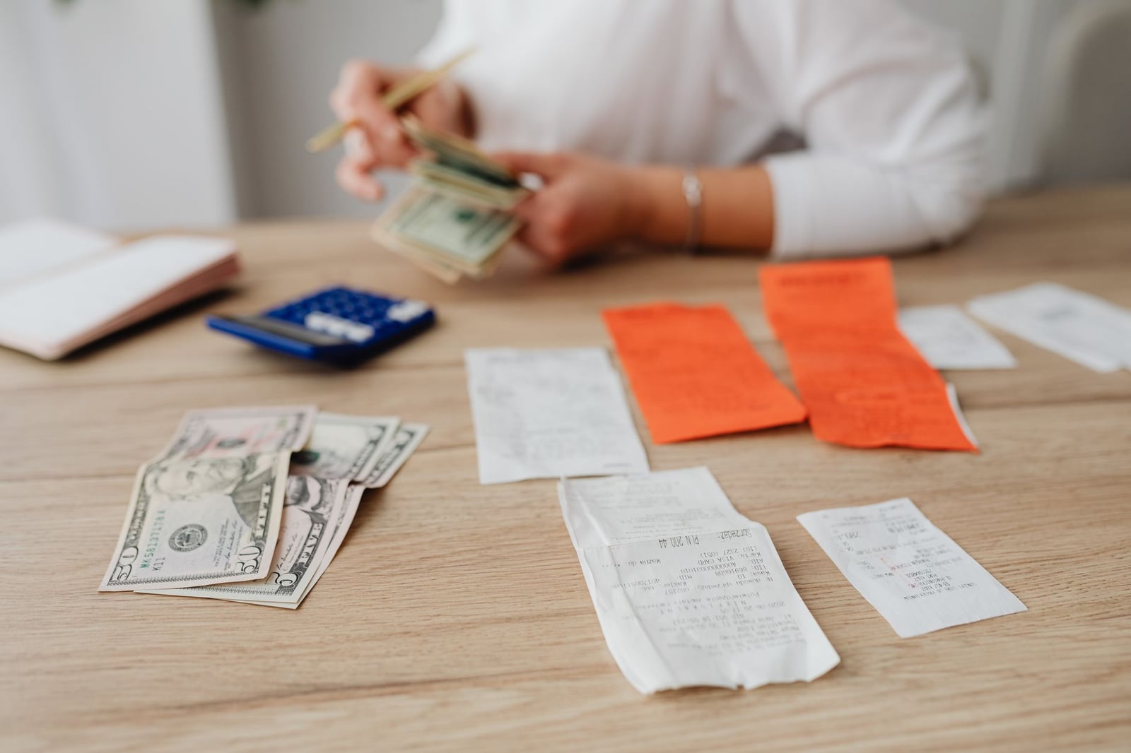 Una persona usando una calculadora y efectivo para planificar un presupuesto doméstico.