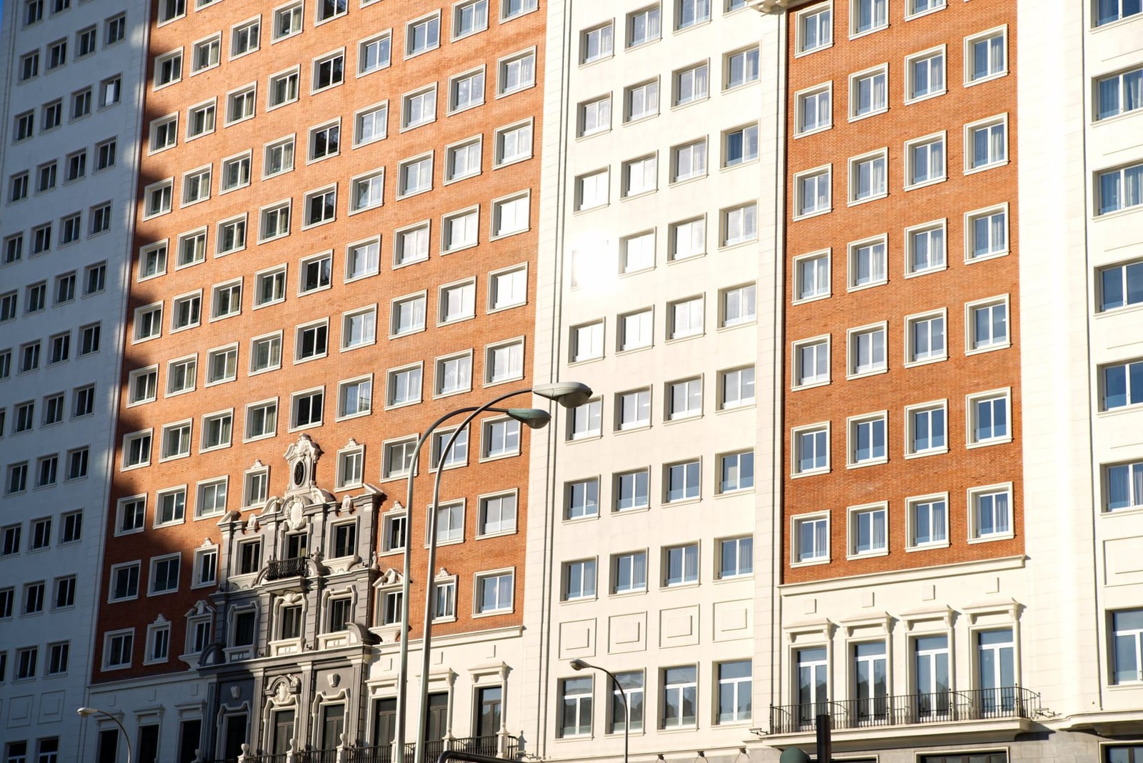 Fachada iluminada por el sol de un clásico edificio residencial con ventanas en Madrid, España.