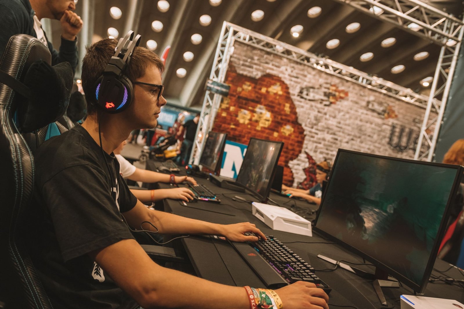 Un joven gamer masculino intensamente concentrado durante un evento de esports en una convención de juegos en interiores.
