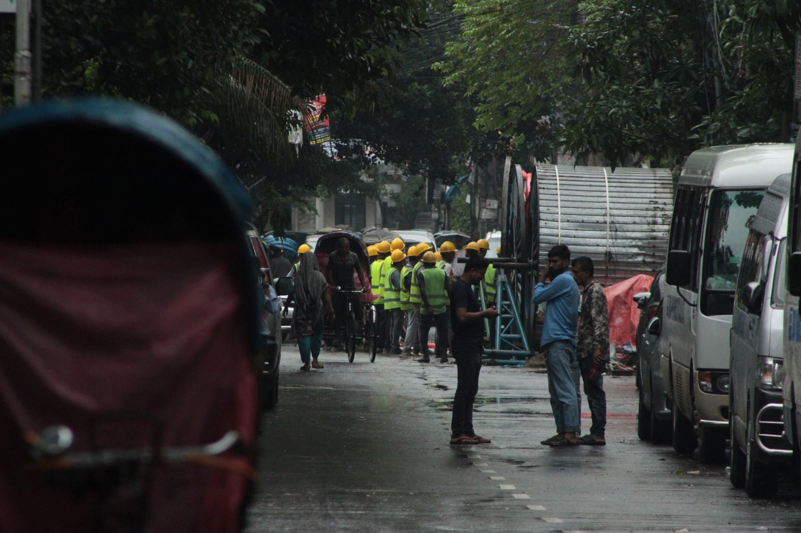 Vista de la calle de trabajadores de la construcción con cascos y chalecos en una zona urbana.