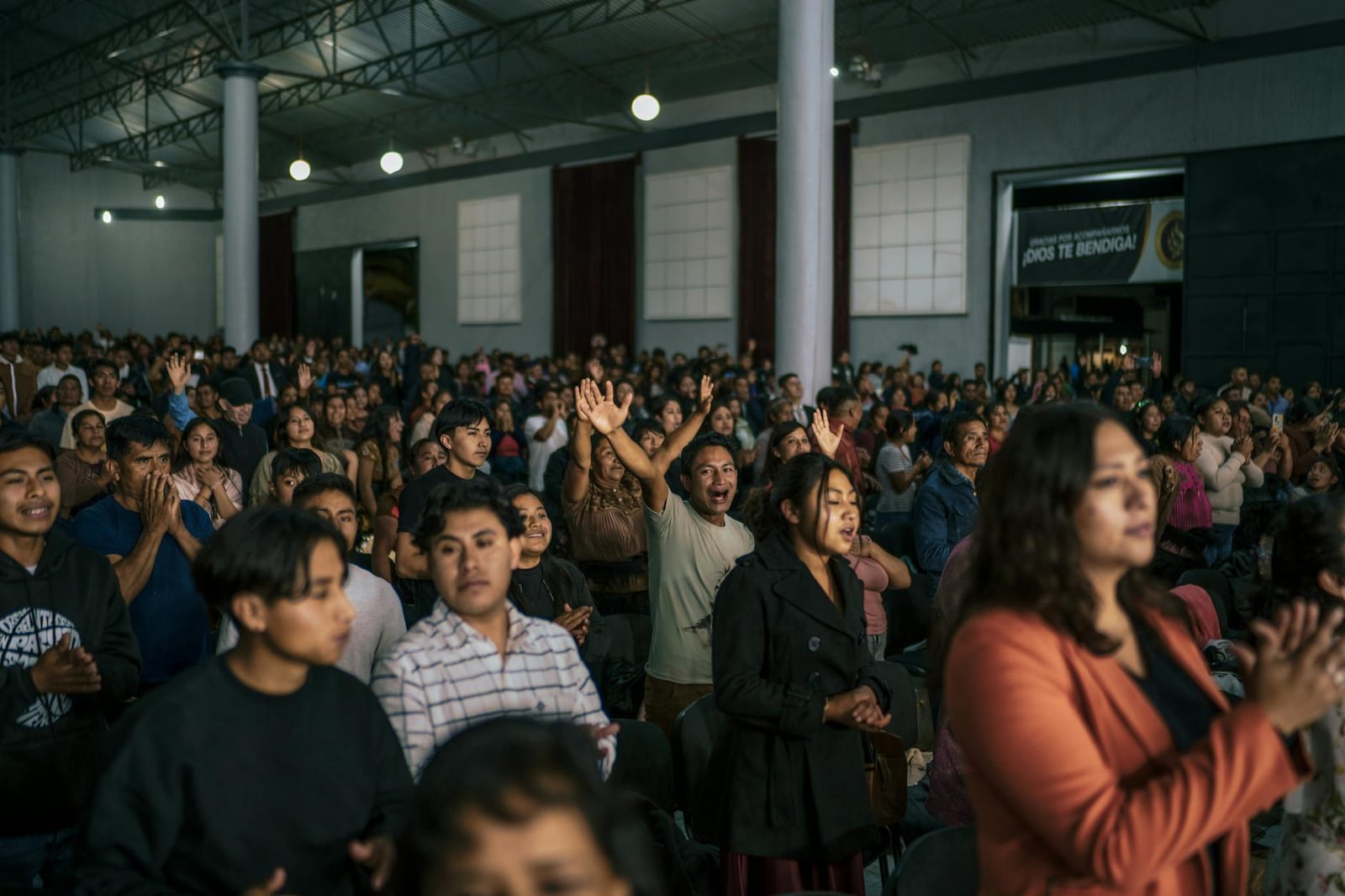 Un servicio de adoración animado con diversos asistentes participando en oración en una iglesia en México.