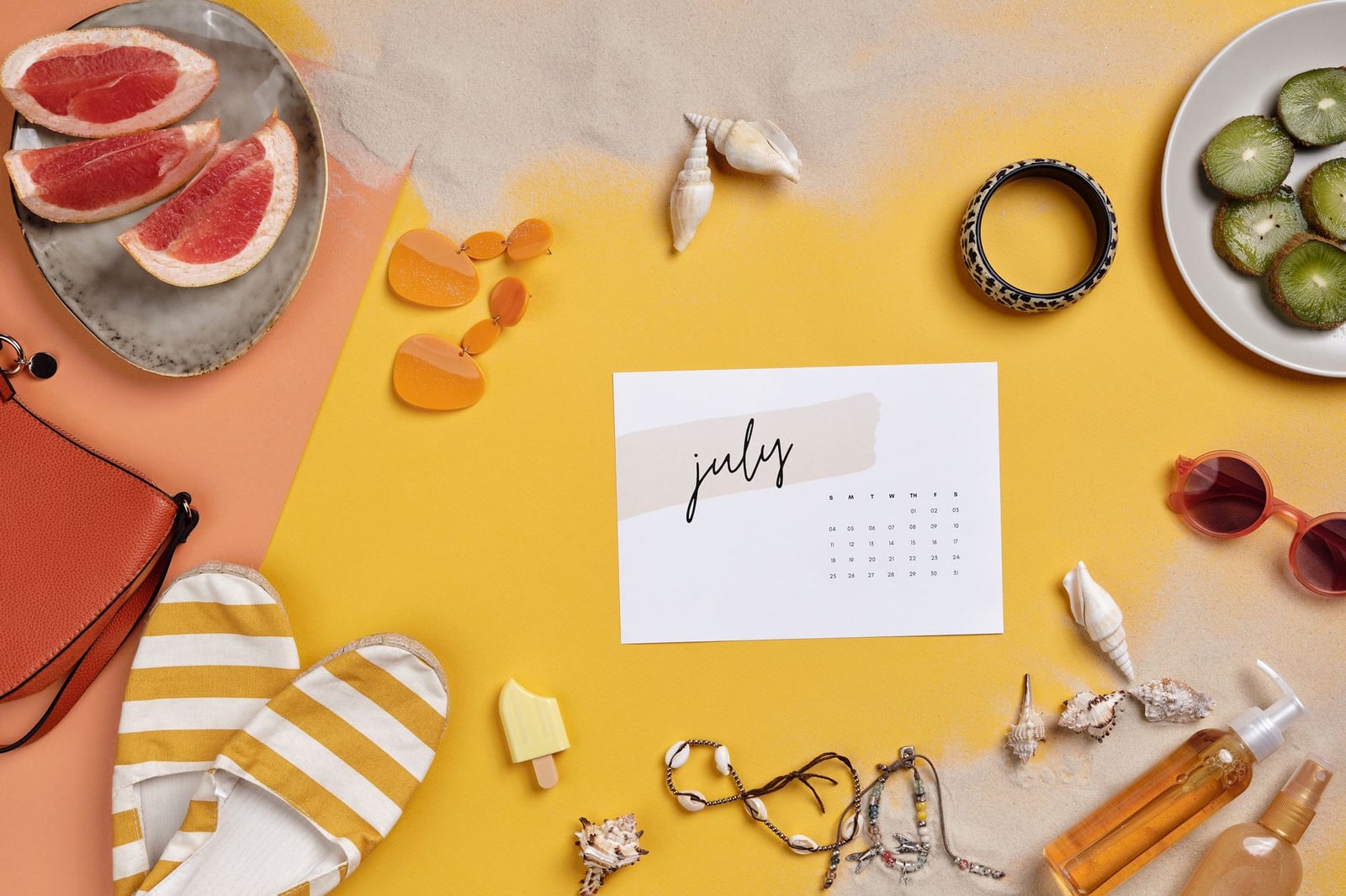 Composición de verano con elementos esenciales de vacaciones como gafas de sol, frutas y calendario sobre arena.