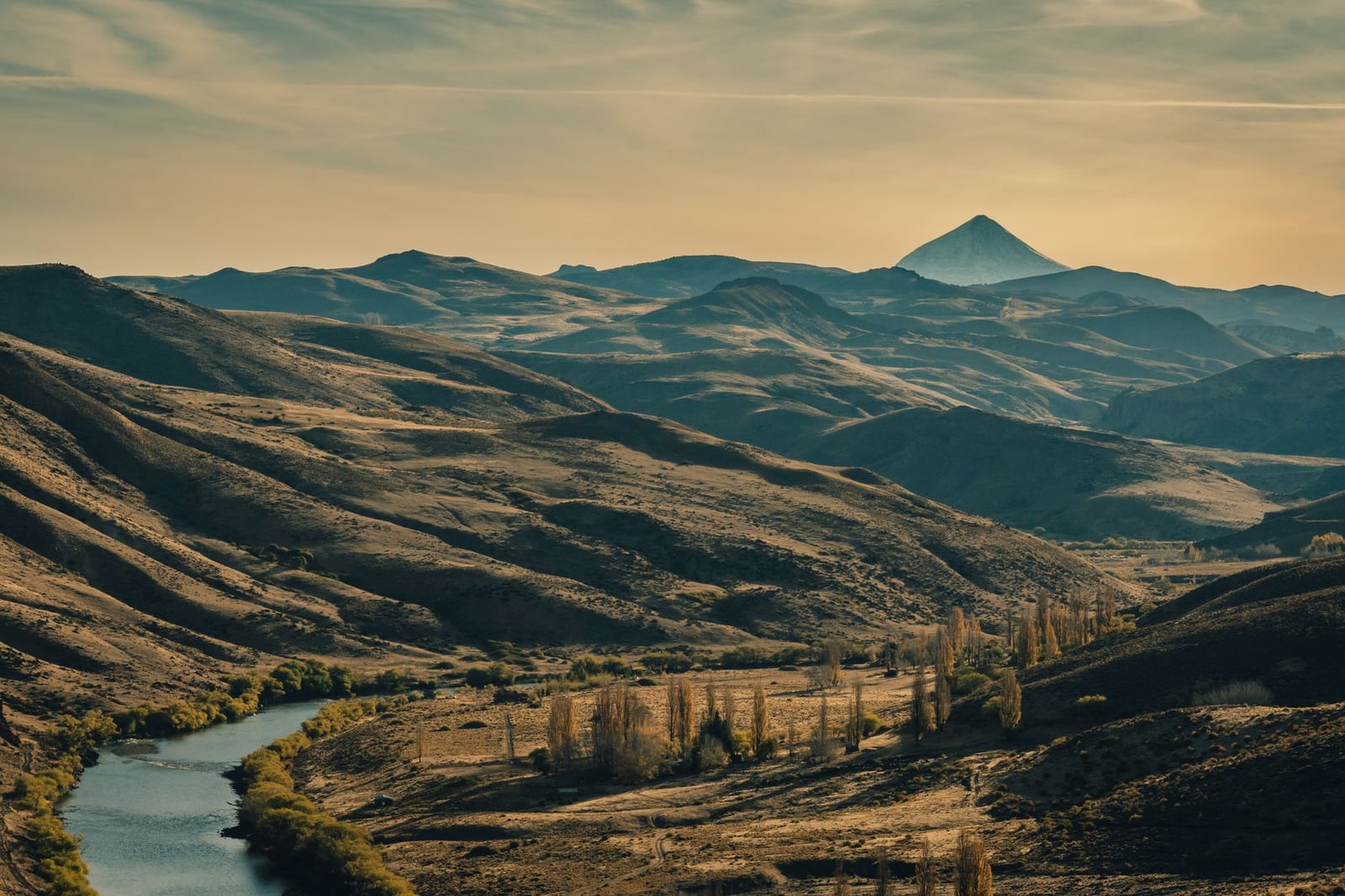 Una vista impresionante de las ondulantes montañas y el río en Neuquén, Argentina, durante la puesta de sol.