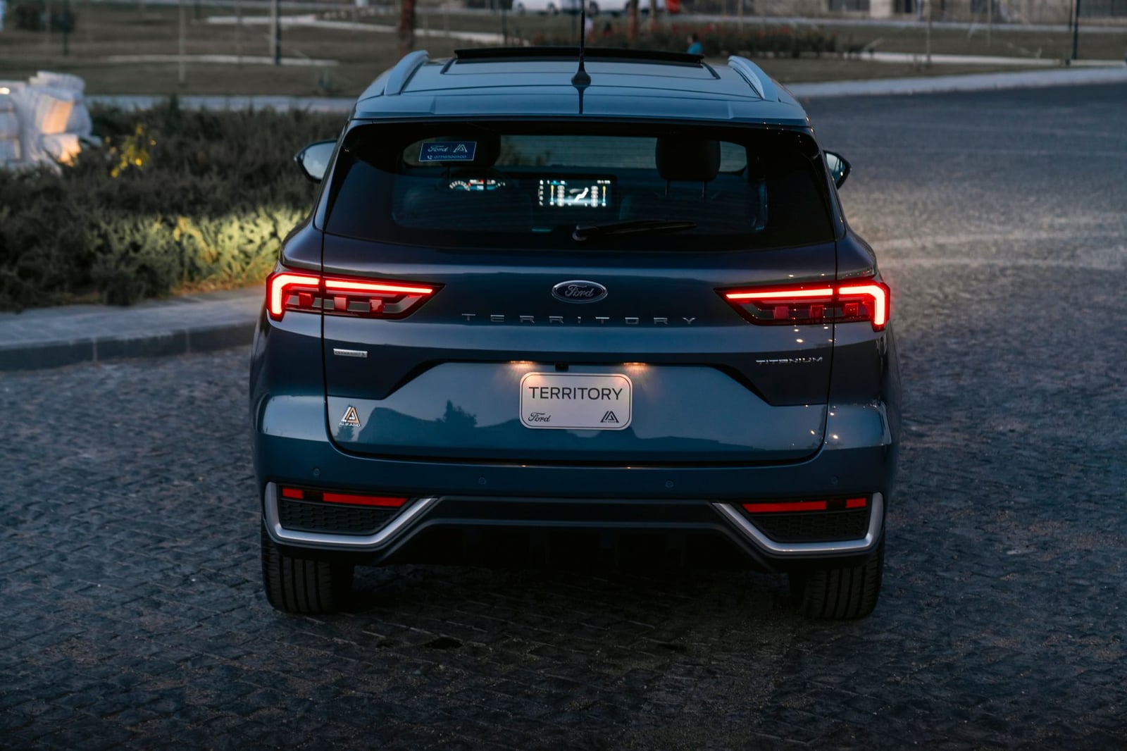 Vista trasera de un SUV azul aparcado en una calle de adoquines al anochecer en Erbil, Irak.
