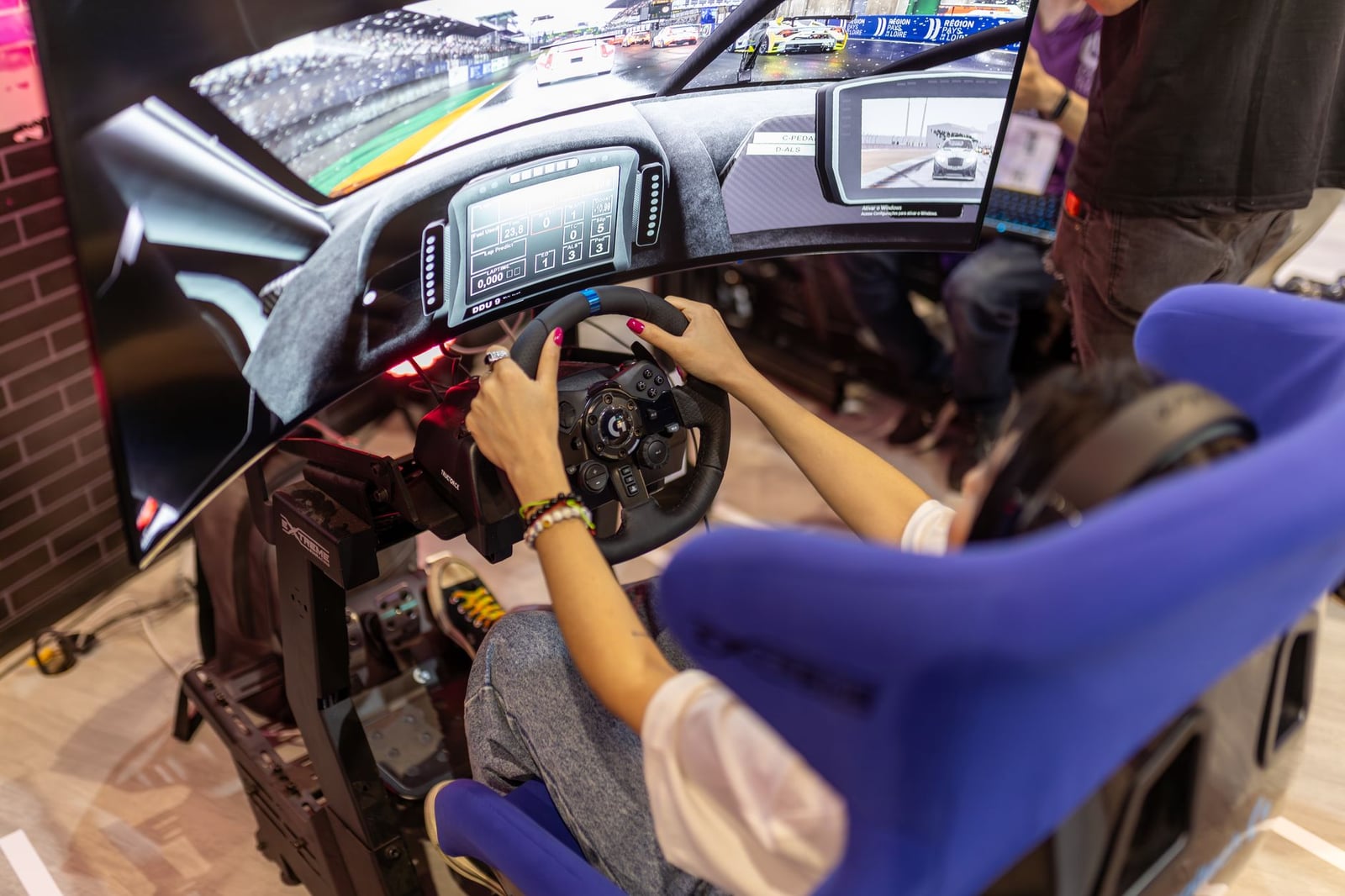 Persona que utiliza un simulador de carreras de realidad virtual realista en un evento de juegos, centrado en la experiencia inmersiva.